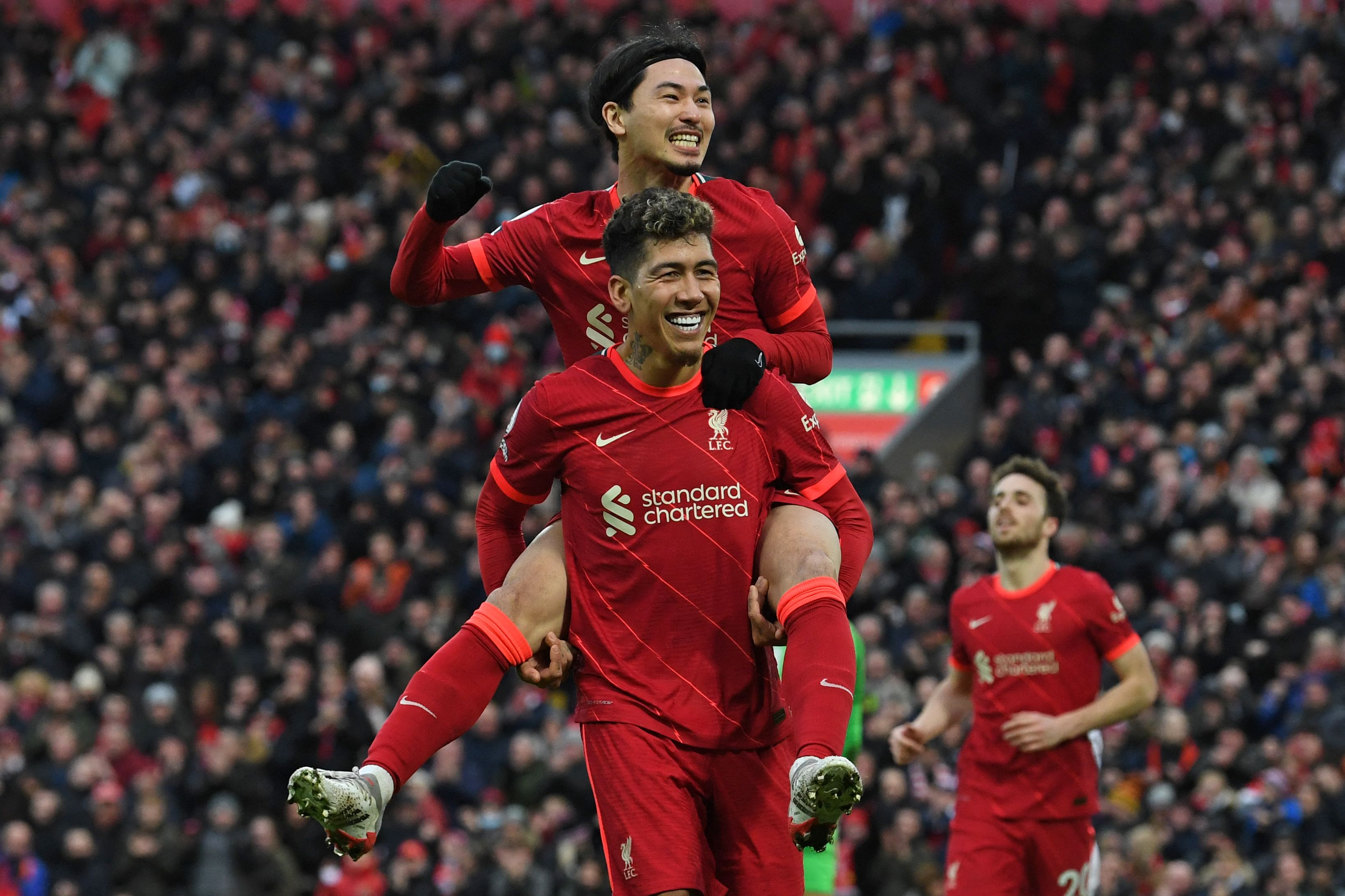 Penyerang Liverpool Roberto Firmino menggendong Takumi Minamino saat merayakan gol ke gawang Brentford di laga Liga Primer Inggris.