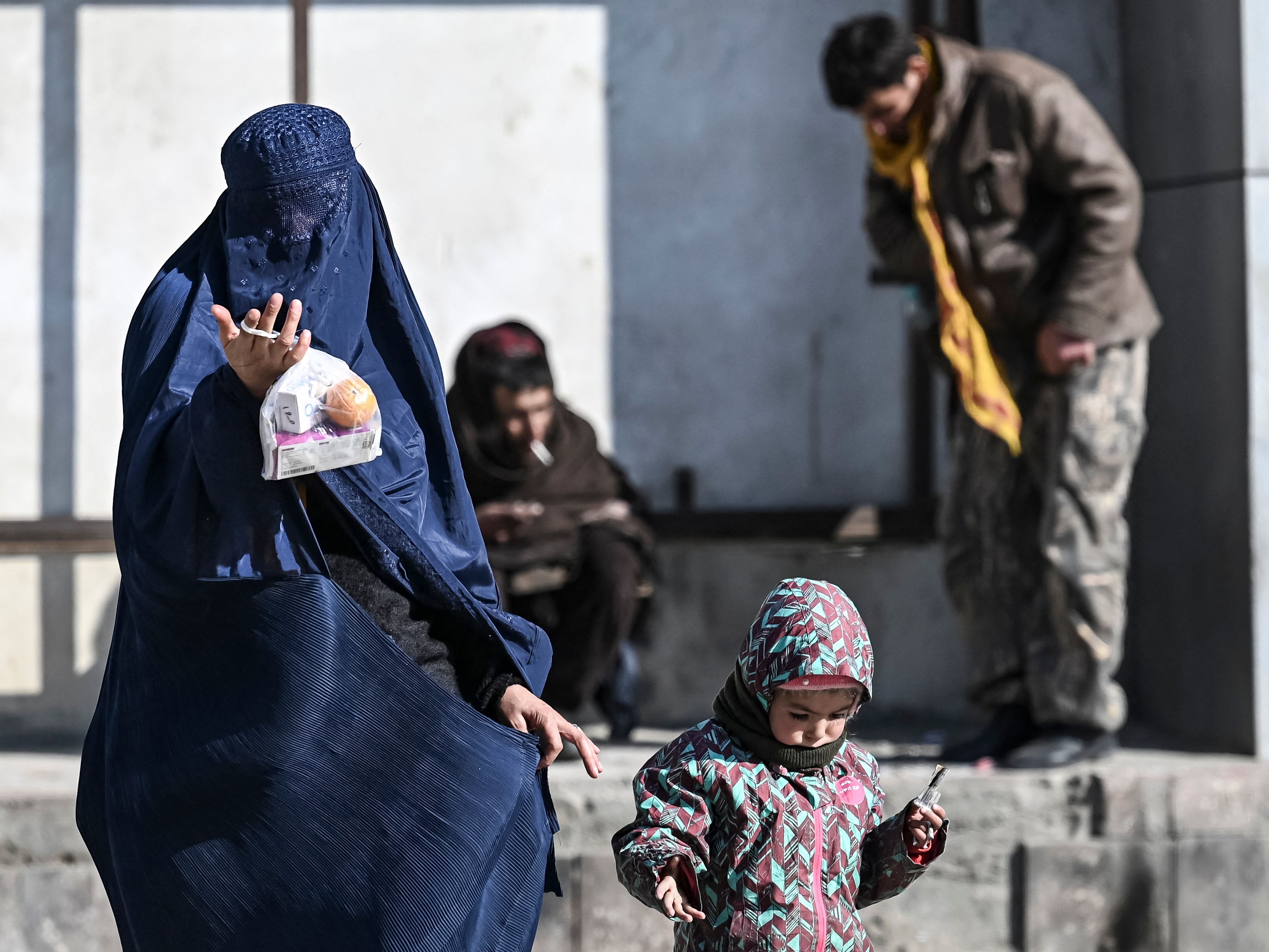Seorang wanita bercadar dengan seorang anak meminta sedekah di jalan, Kabul, pada 14 Januari 2022.