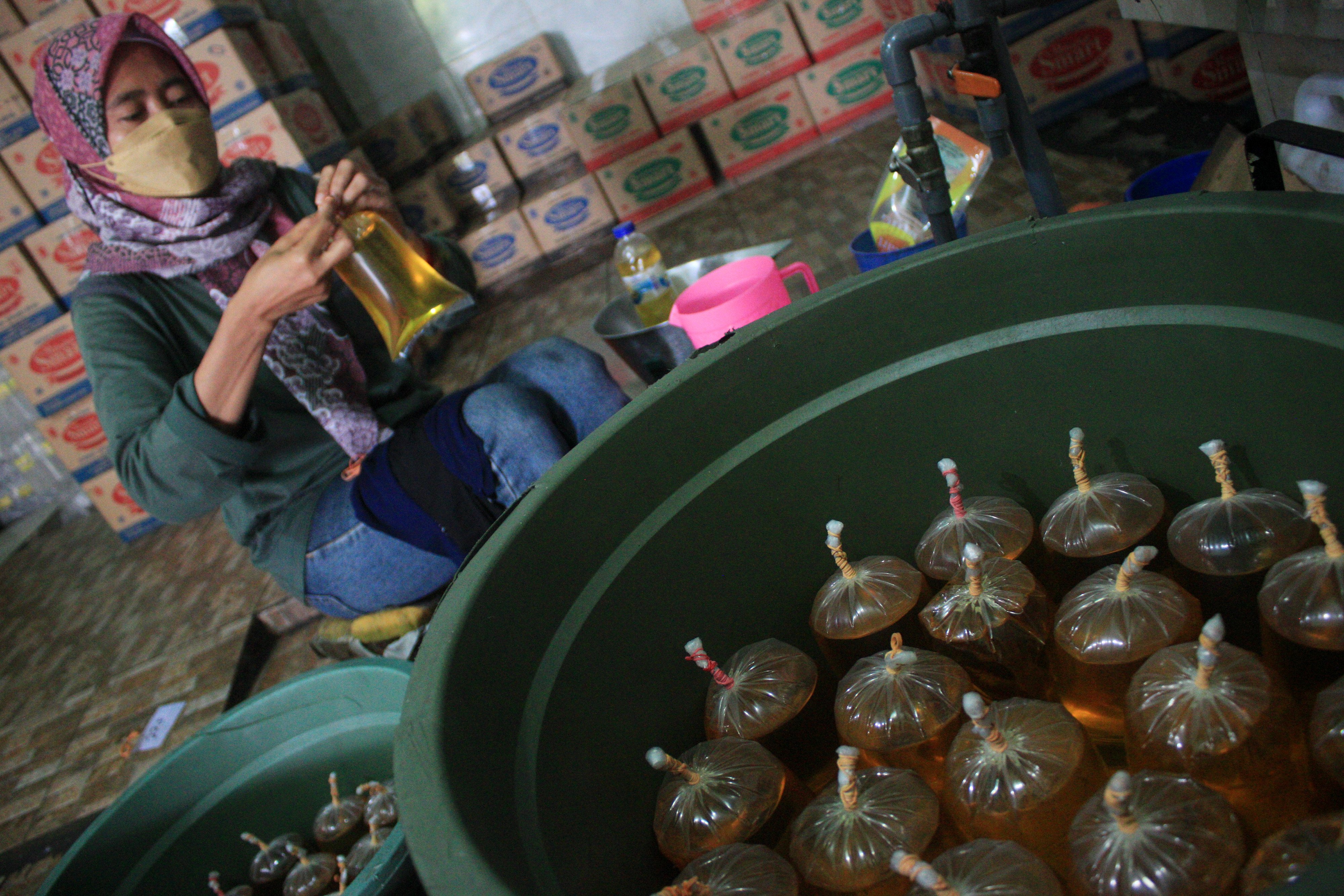 Pekerja mengemas minyak goreng curah ke dalam kantong plastik di salah satu agen penjualan minyak goreng curah di Surabaya, Jawa Timur, Rabu