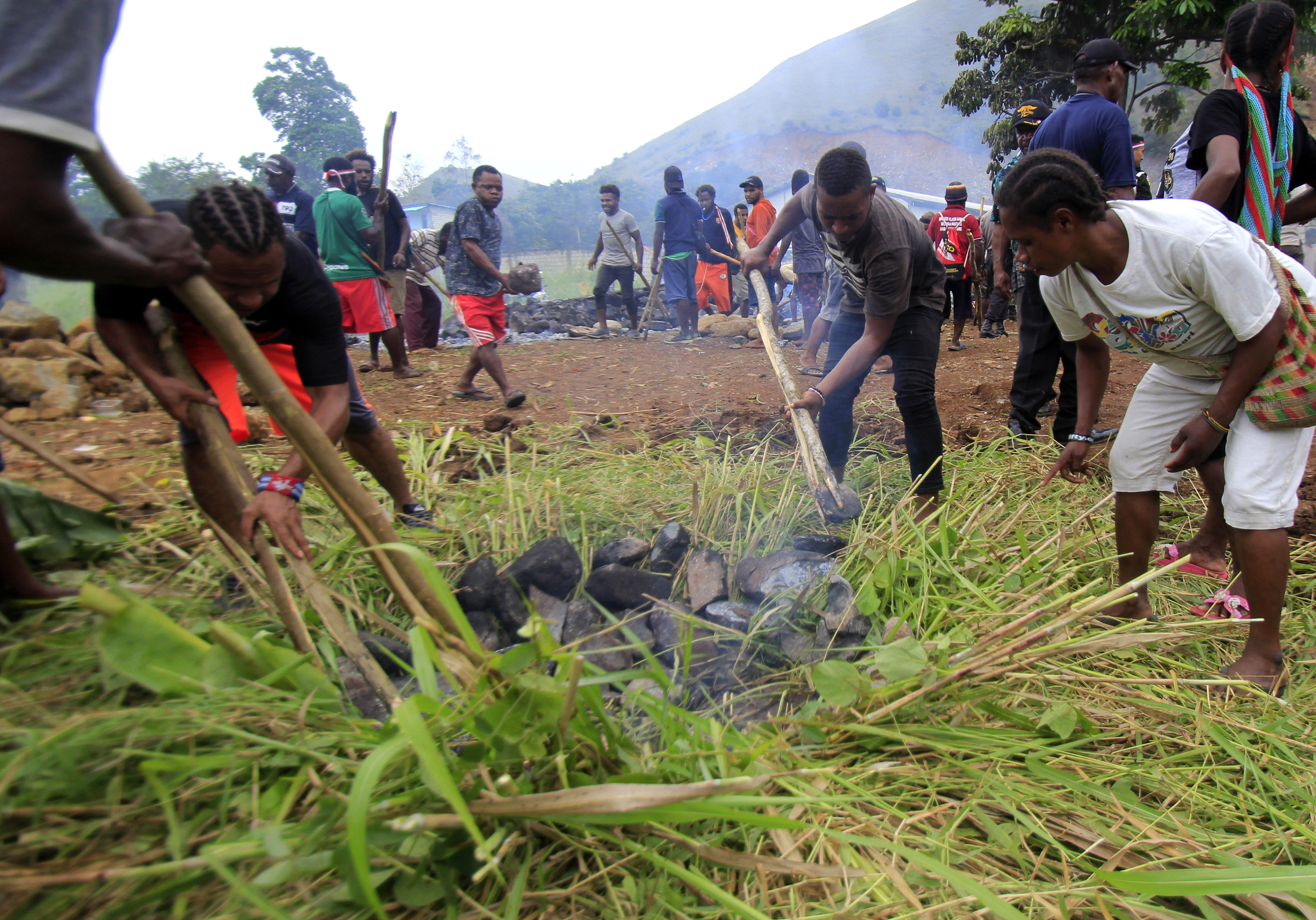  Masyarakat Papua melakukan upacara bakar batu di lapangan Hawai, Sentani, Papua, sebagai tanda perdamaian. 