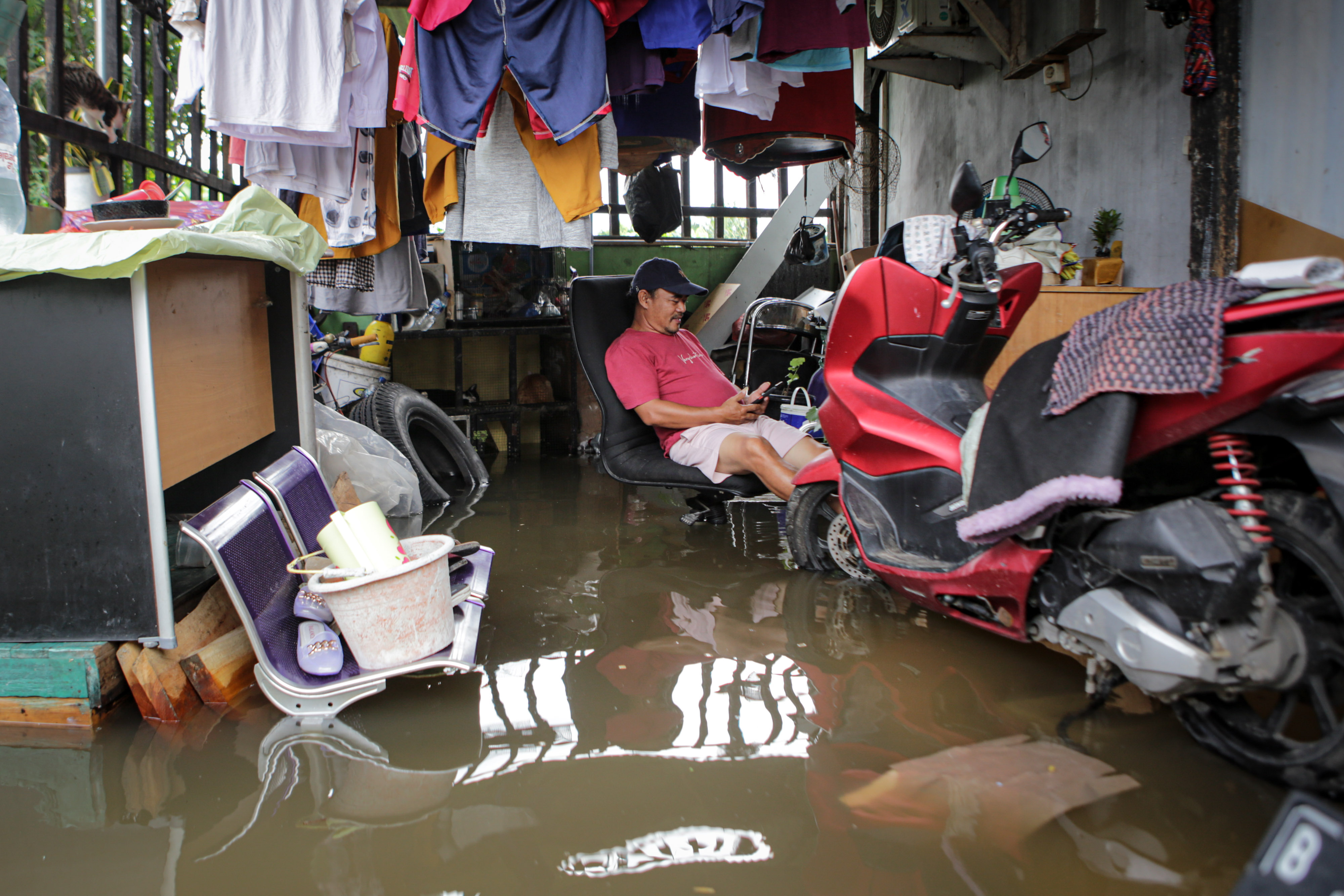 Seorang warga duduk di halaman rumahnya yang terendam banjir di kawasan Benda, Kota Tangerang, Banten, Rabu (19/1/2022).