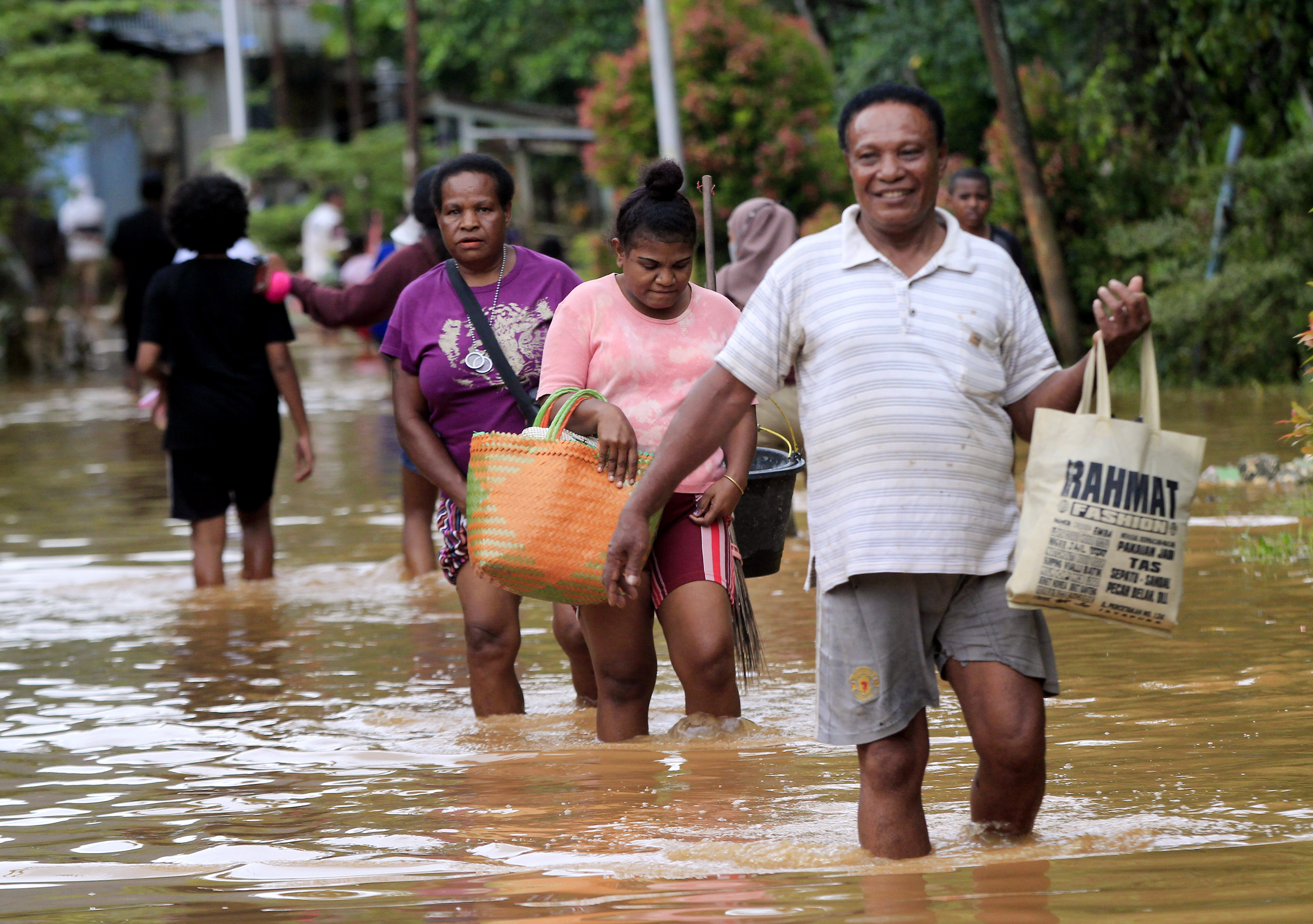 Sejumlah mama-mama Papua melintasi daerah yang terendam banjir di Perumahan Organda, Distri Heram, Kota Jayapura, Papua, Minggu (9/1/2021)
