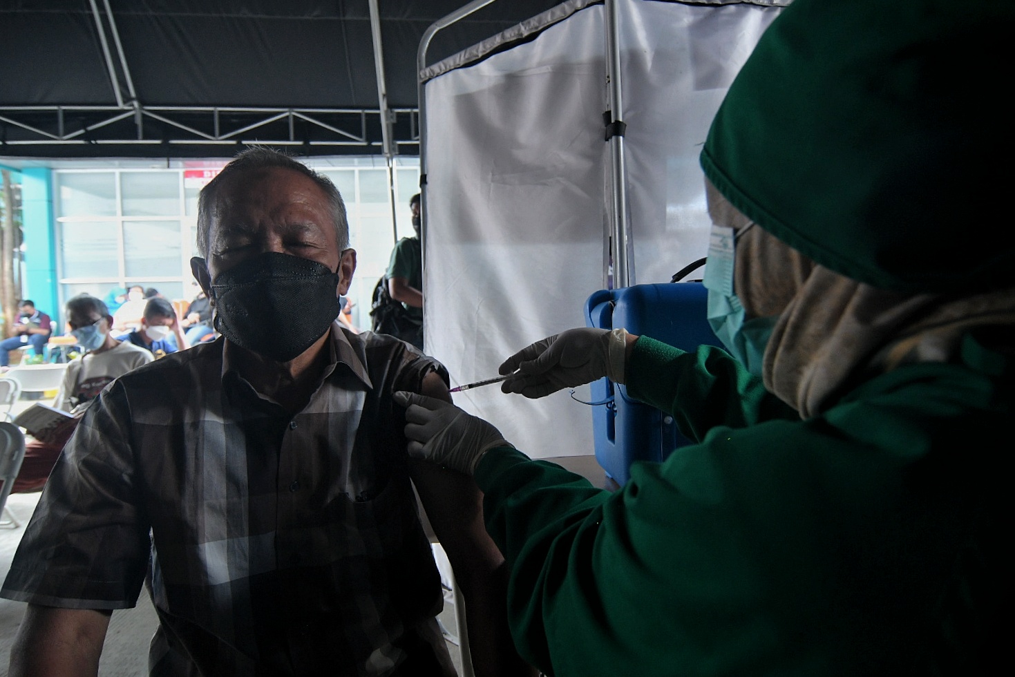 Nakes menyuntikkan vaksin covid-19 booster pada warga di Puskesmas Kecamatan Kramat Jati, Jakarta Timur.