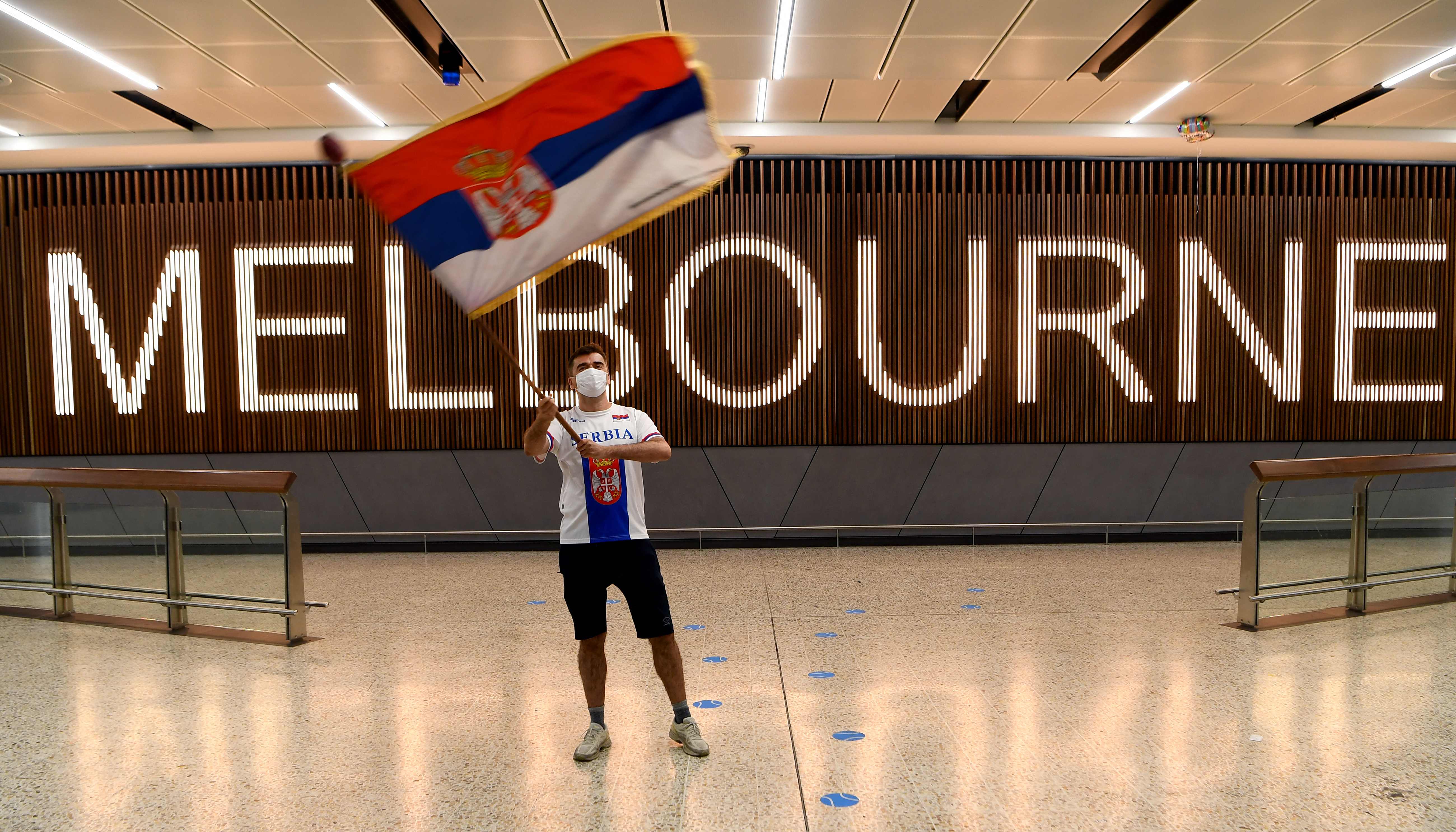 Seorang pendukung mengibarkan bendera Serbia saat menunggu kedatangan Novak Djokovic di Bandara Melbourne.