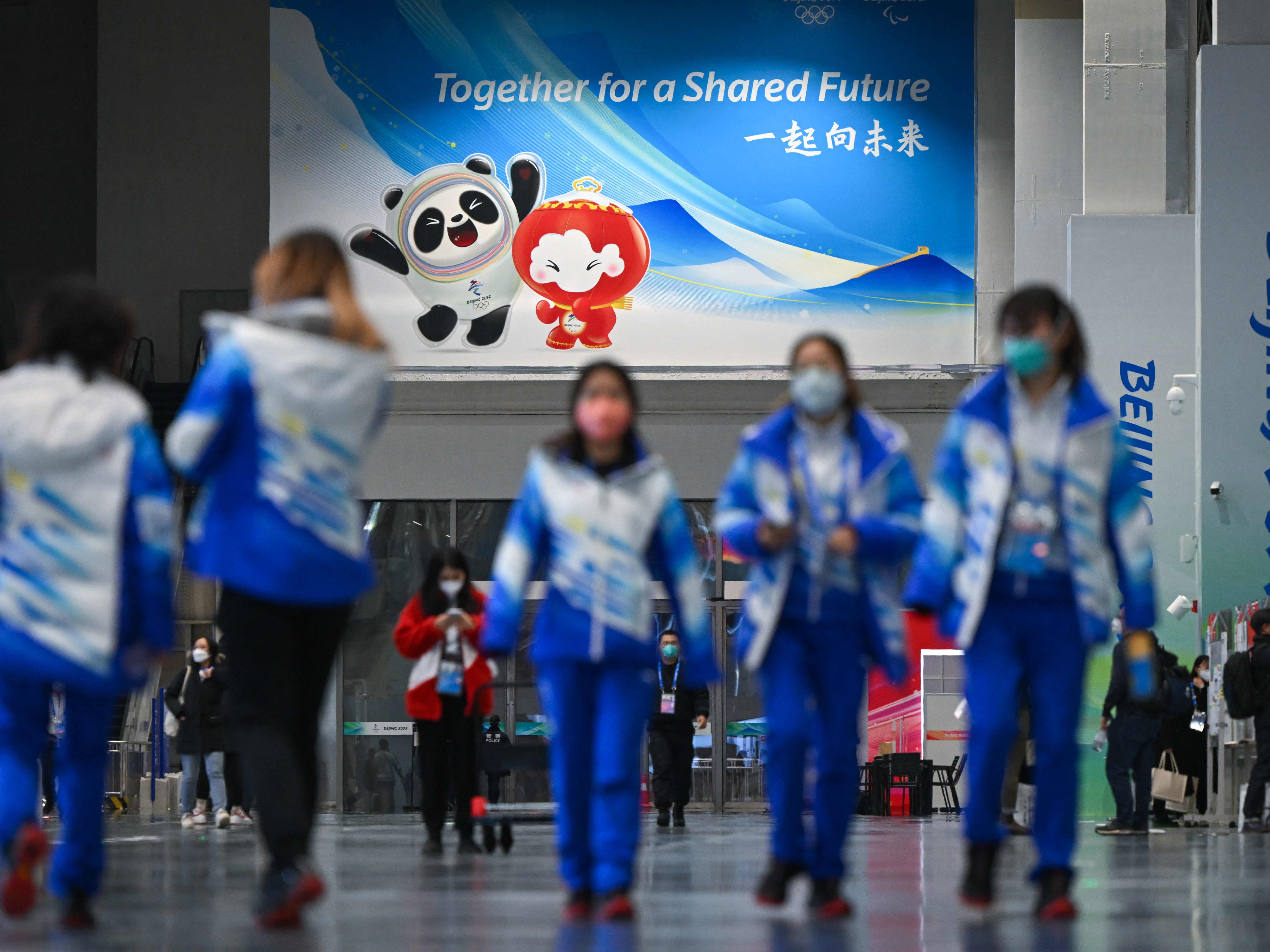 Relawan Olimpiade Musim Dingin Beijing 2022 berjalan di Pusat Pers Utama di Beijing pada 28 Januari 2022.