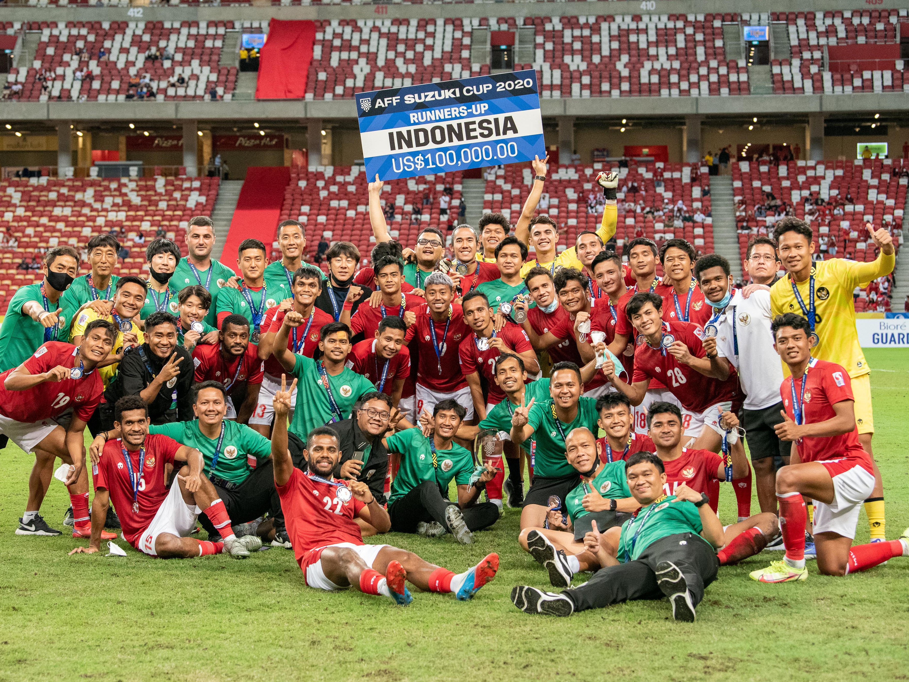 Pesepak bola dan tim pelatih Timnas Indonesia berfoto bersama usai pengalungan medali Piala AFF 2020 di National Stadium, Singapura.
