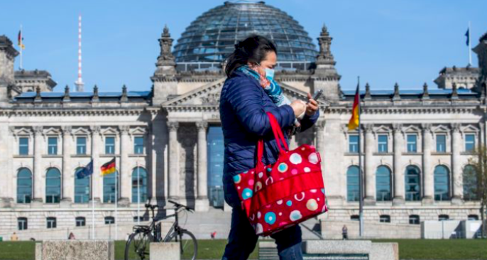 Seorang warga mengenakan masker melintas di depan gedung parlemen Jerman di Berlin.