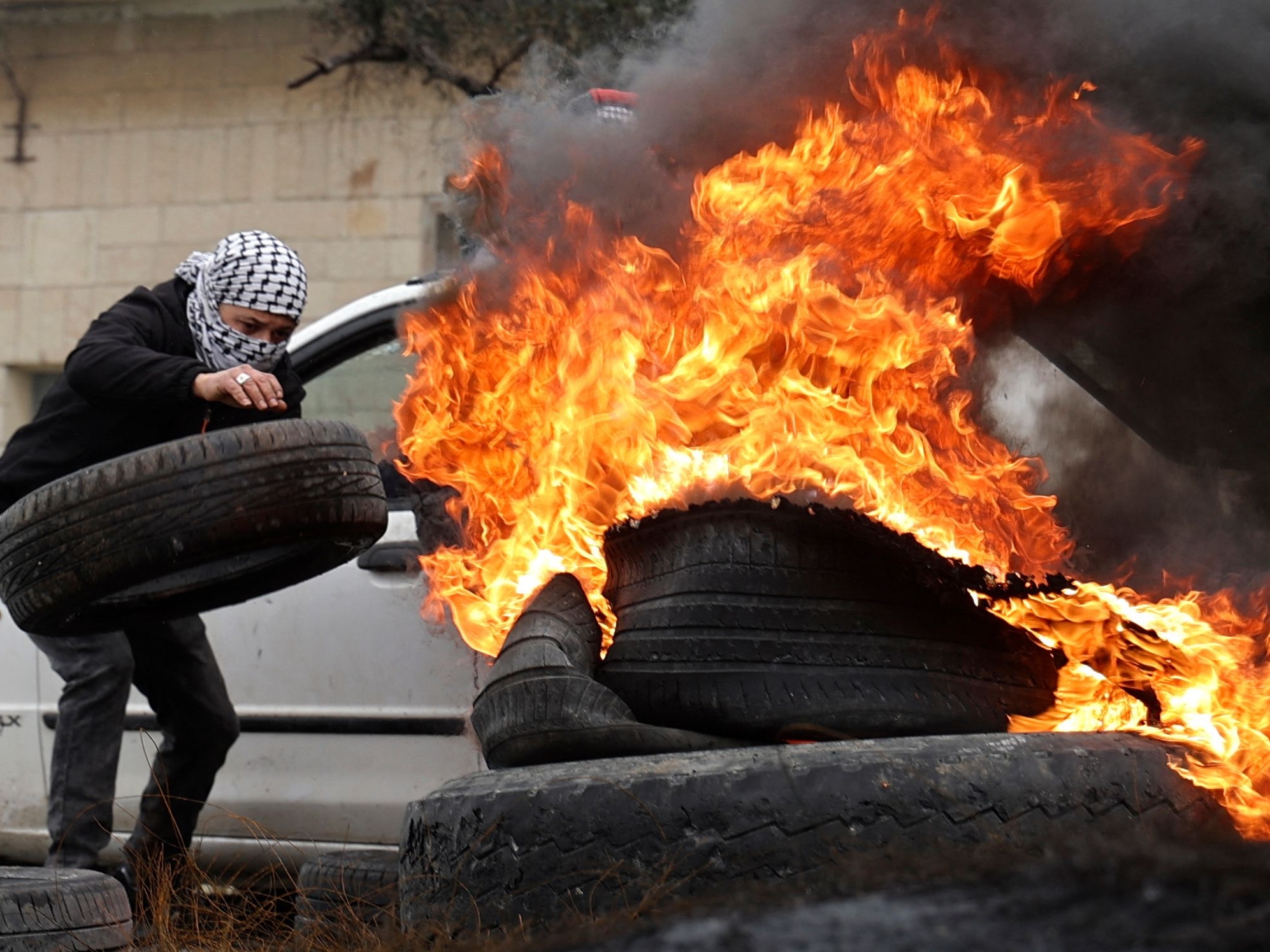 Pemuda Palestina membakar ban selama konfrontasi dengan pasukan keamanan Israel, menyusul demonstrasi menentang pengambilalihan tanah.