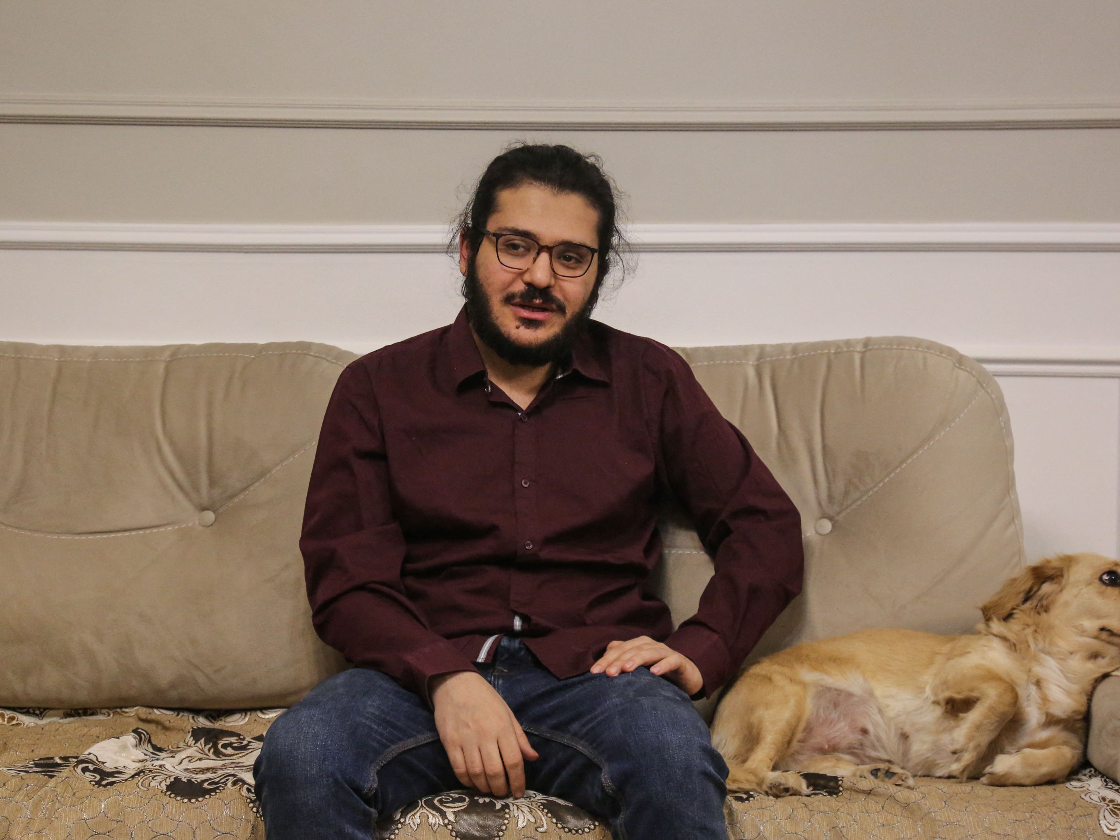 Peneliti Mesir Patrick Zaki berfoto di sebelah seekor anjing dalam rumah keluarganya, Kairo, 9 Desember 2021, setelah pembebasannya.