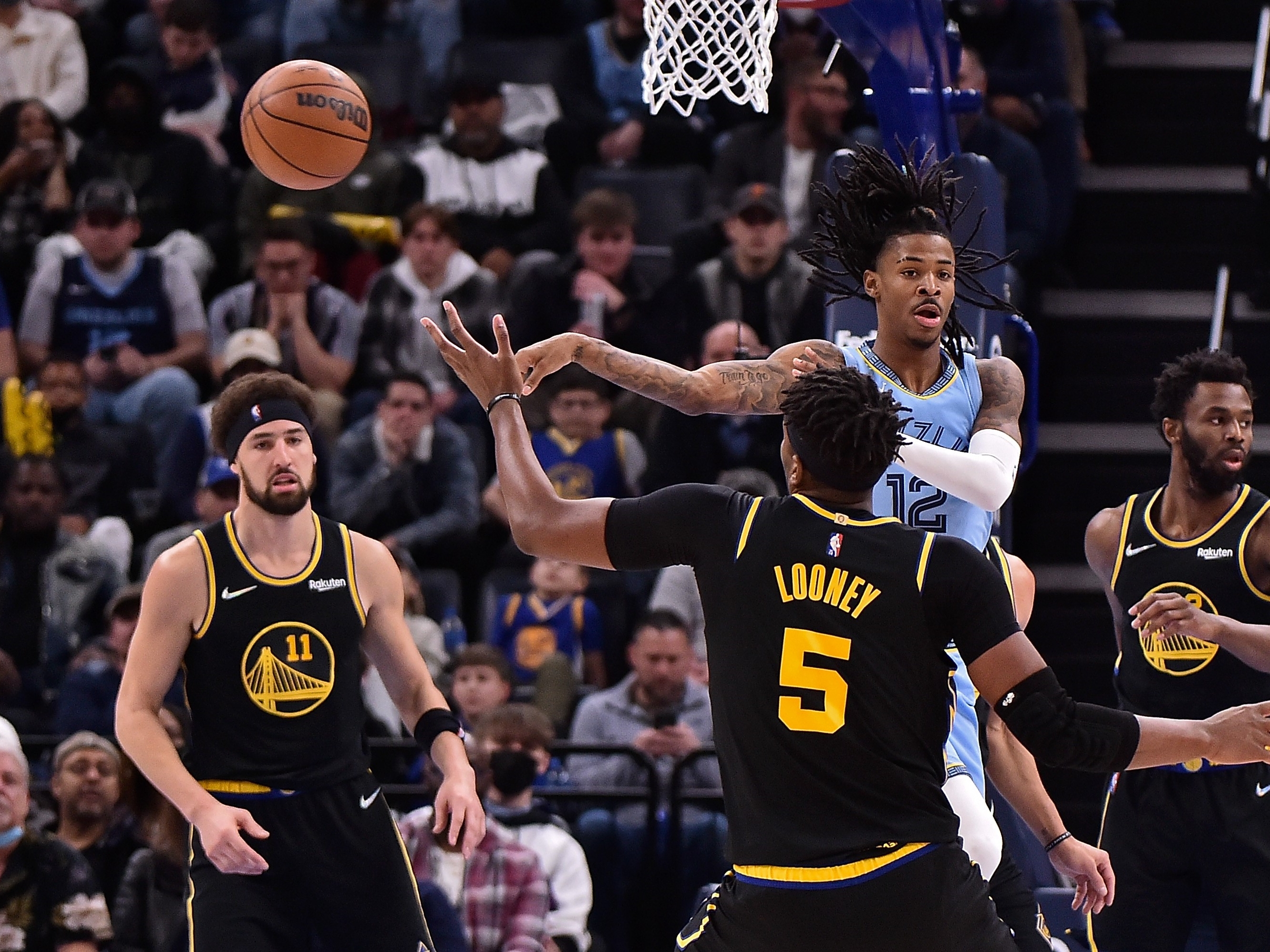 Ja Morant #12 dari Memphis Grizzlies melewati Kevon Looney #5 dari Golden State Warriors selama babak pertama di FedExForum, Selasa (11/1)