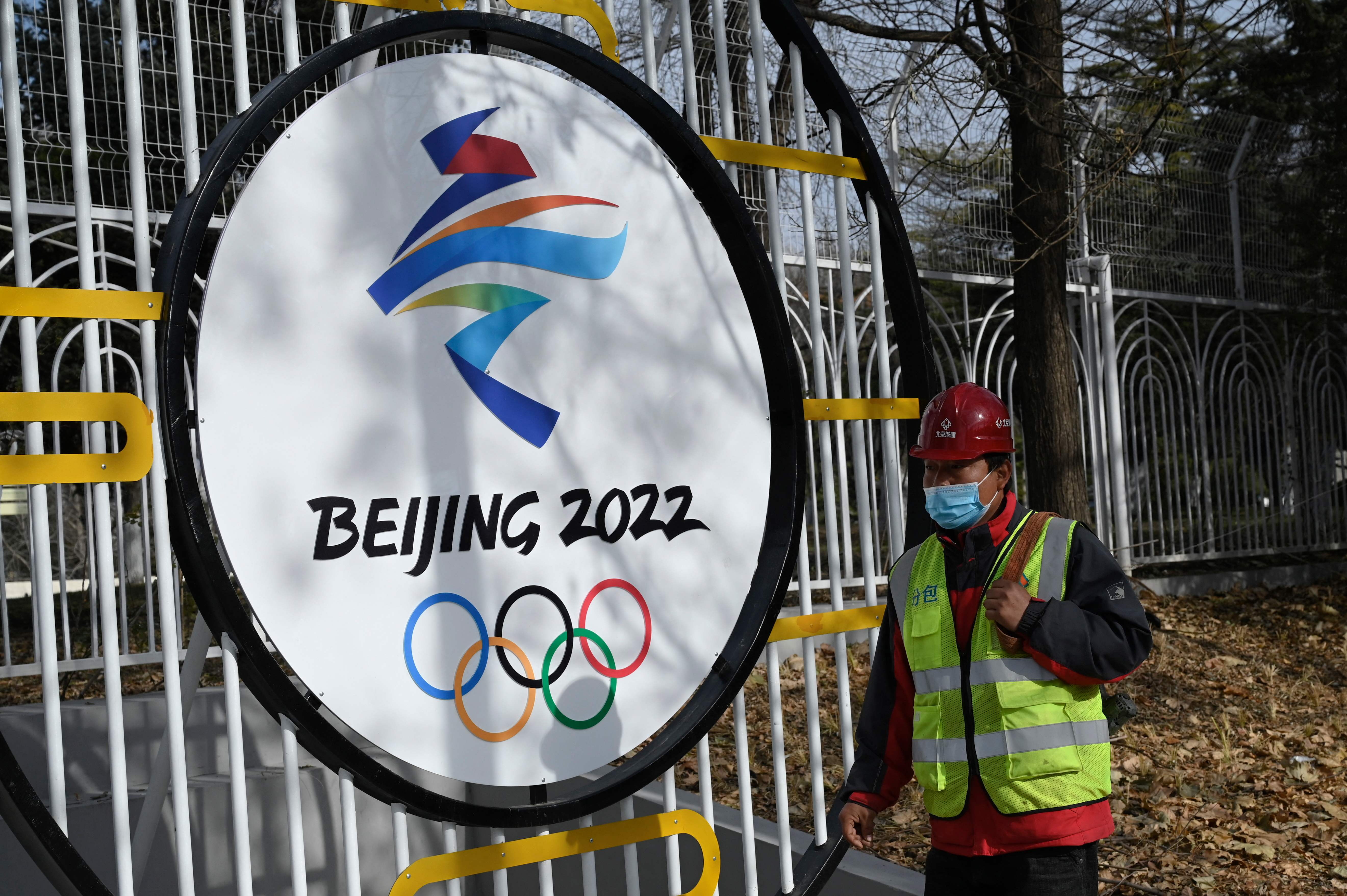 Seorang pekerja melintas di depan logo Olimpiade Beijing 2022