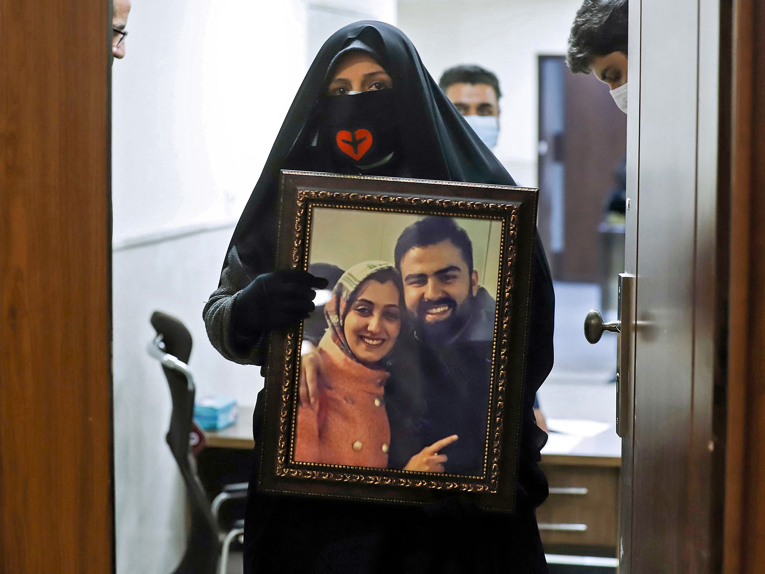 Seorang wanita memegang potret orang yang dicintai yang tewas dalam jatuhnya pesawat Ukraina pada 2020.