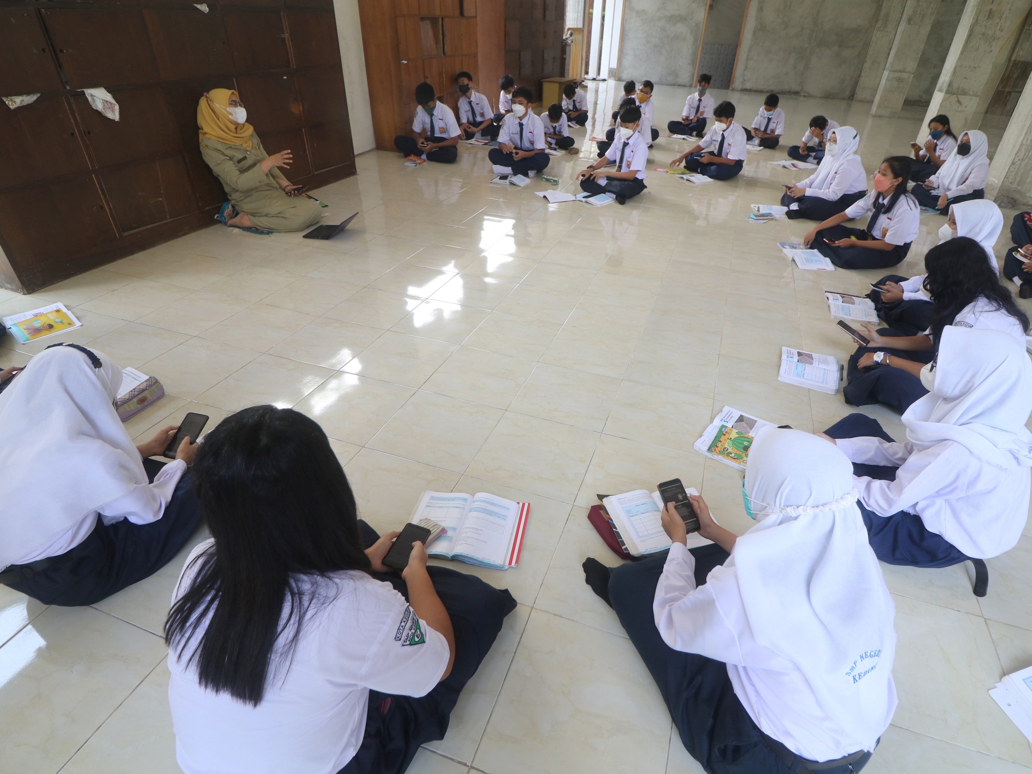 Siswa mengikuti pelajaran Bahasa Indonesia saat pembelajaran tatap muka 100% hari pertama di SMP Negeri 1 Kota Kediri, Jattim, Senin (10/1).