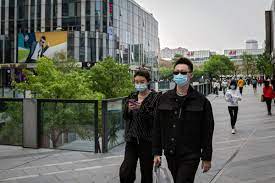 Ilustrasi : Orang-orang memakai masker di tengah kekhawatiran covid-19 berjalan di luar pusat perbelanjaan di Beijing, Minggu (19/4). 