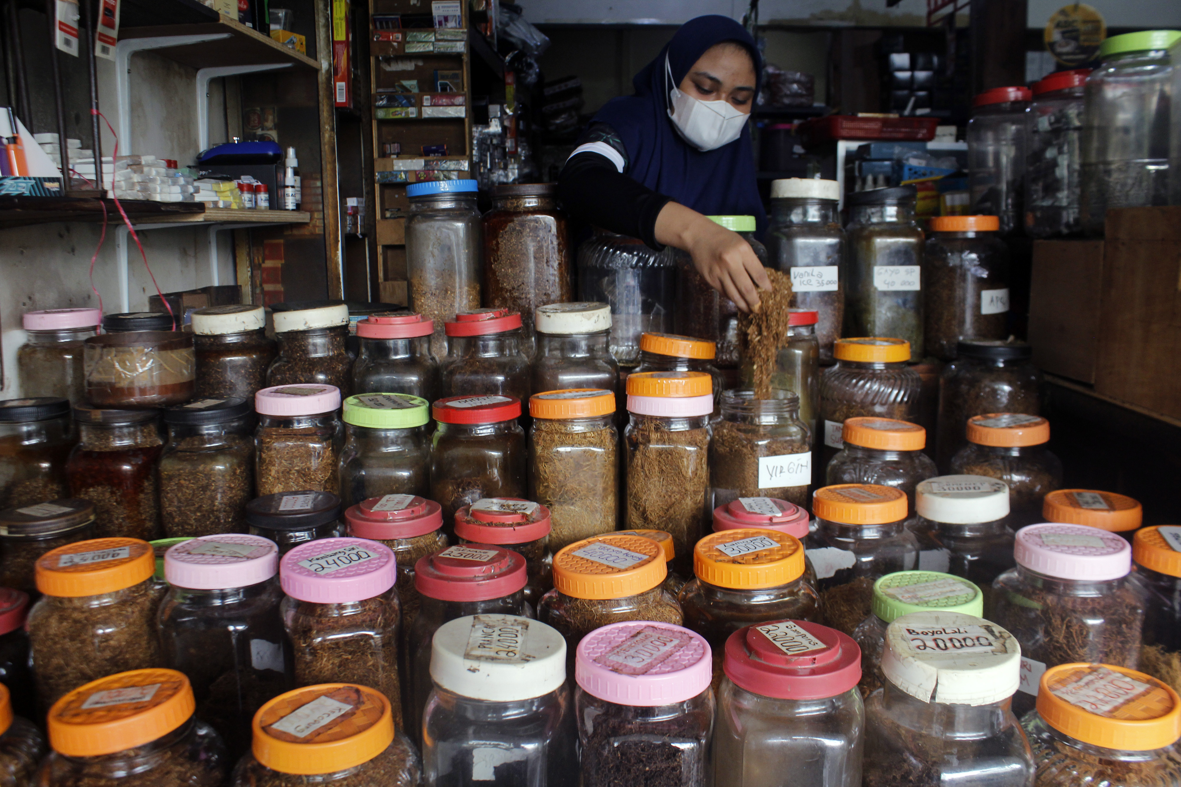 Pedagang mengambil tembakau linting pesanan pelanggganya di salah satu toko tembakau di Surabaya, Jawa Timur, Kamis (6/1).