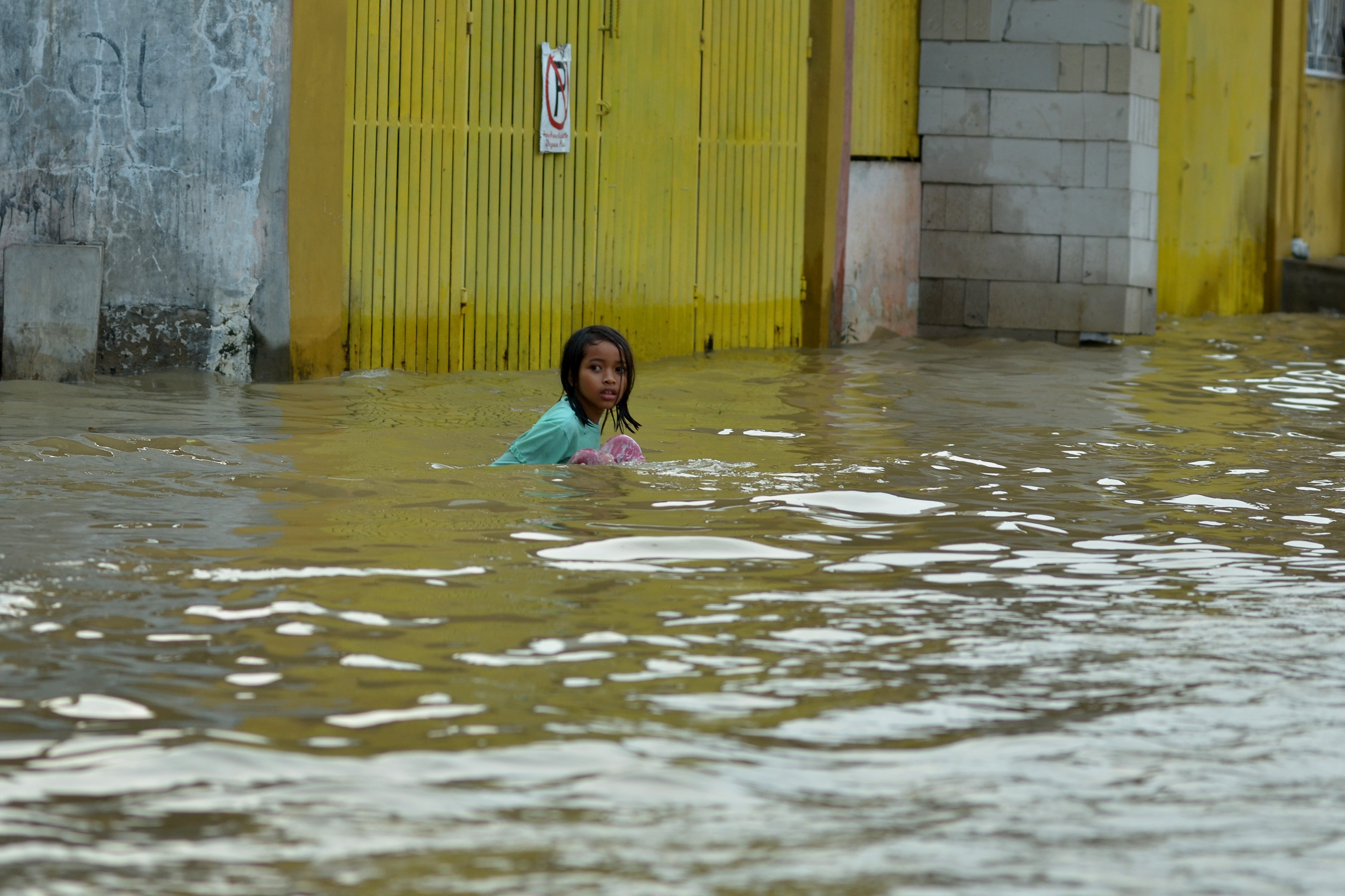 Seorang anak bermain banjir di Perumahan Villa Indah Permai, Bekasi, Jawa Barat, Minggu (16/1).