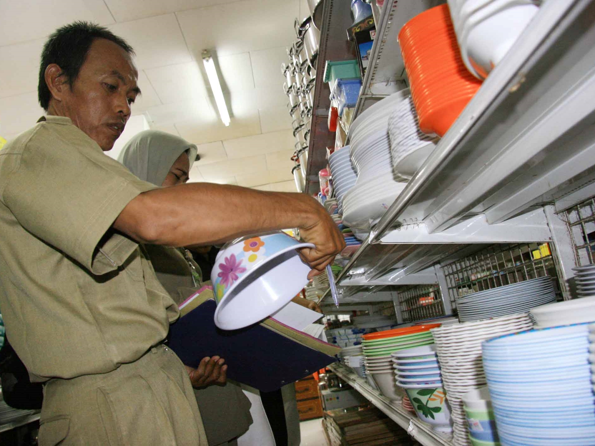 Ilustrasi sejumlah petugas memeriksa tumpukan piring saat razia peralatan makan bermelamin di salah satu supermarket. 