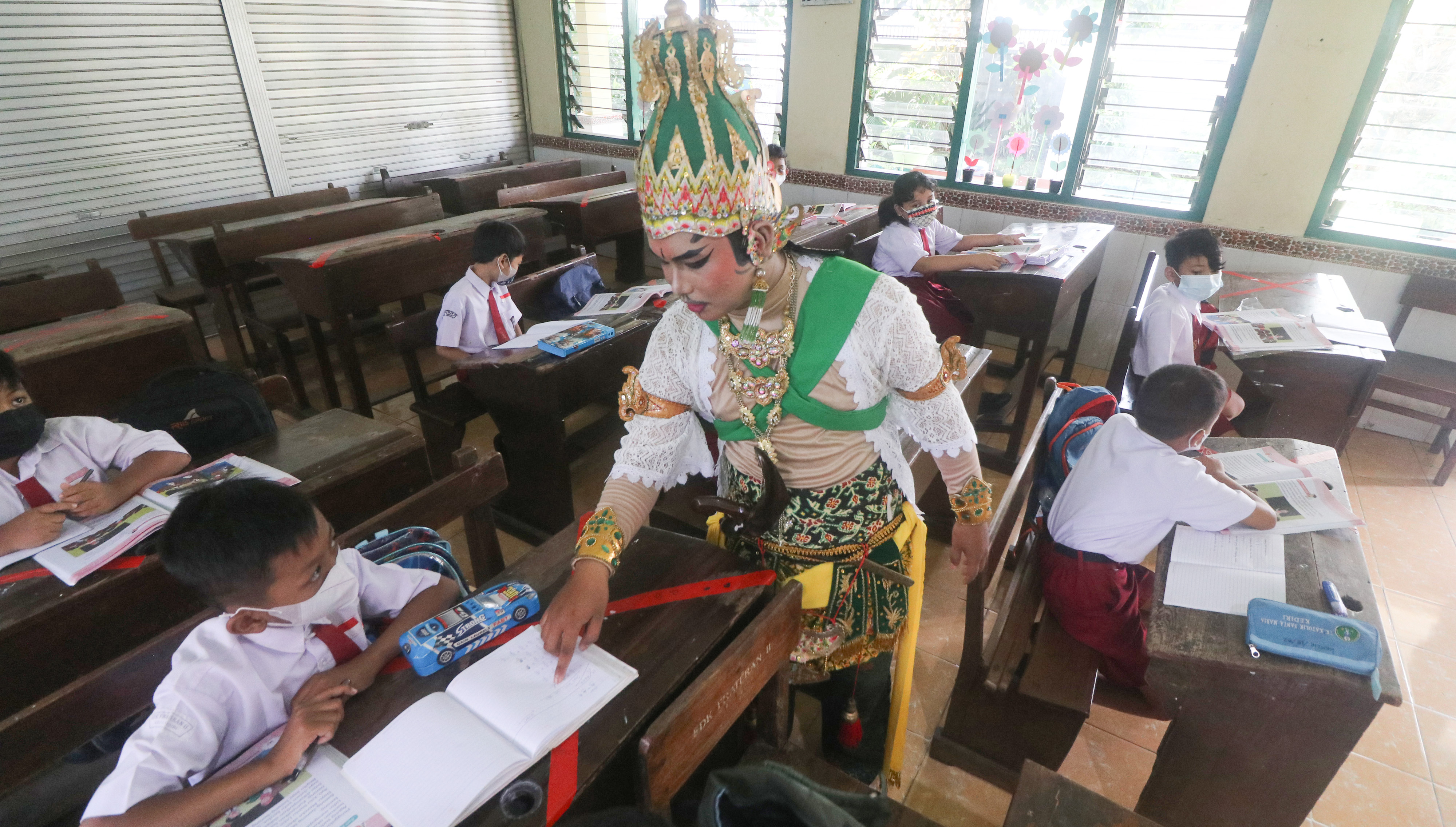 Seorang guru berkostum wayang orang mengajar di SD Katolik Frateran II, Kota Kediri, Jawa Timur, Senin (17/1/2022).