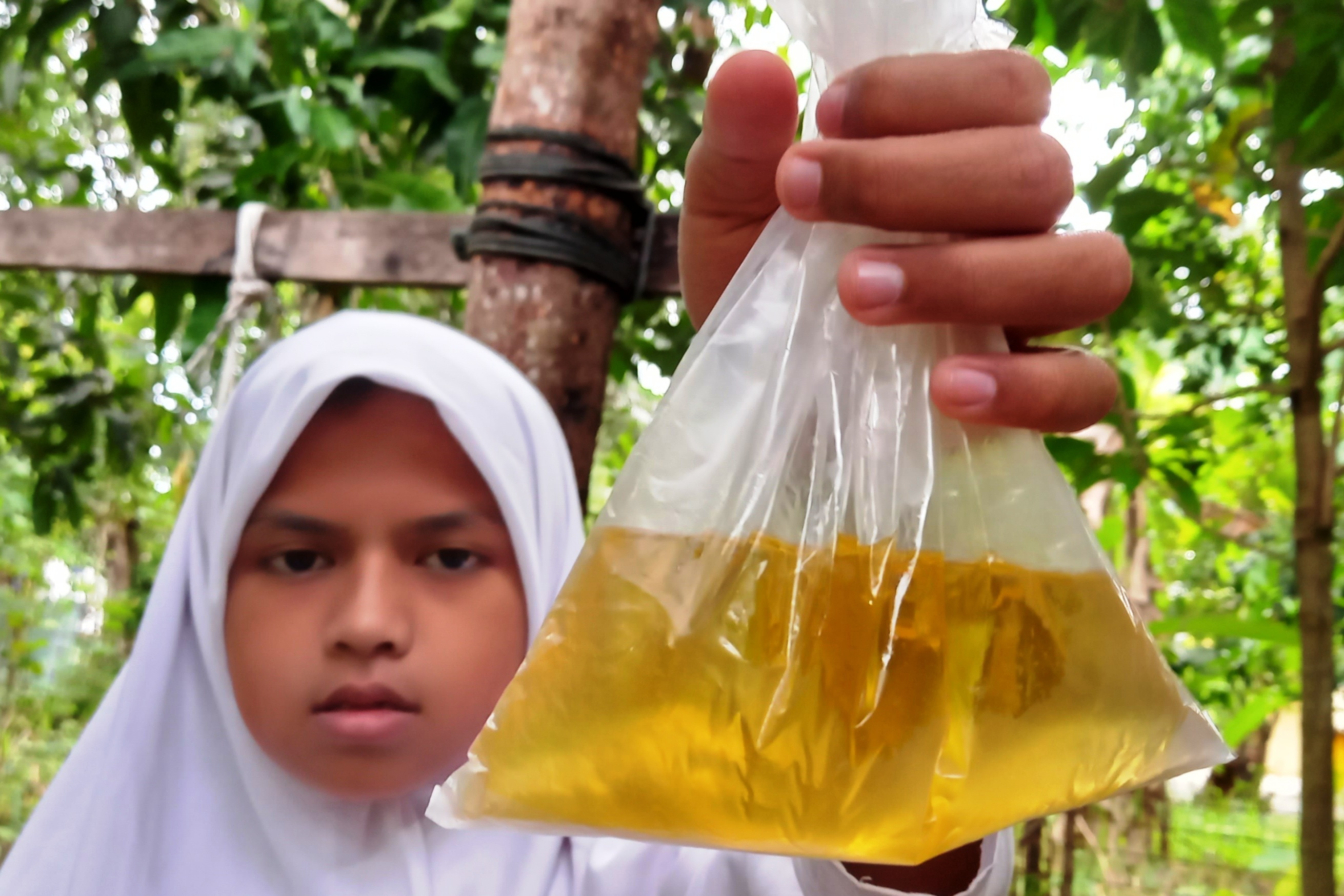 Seorang anak sedang memperlihatkan minyak goreng curah. 