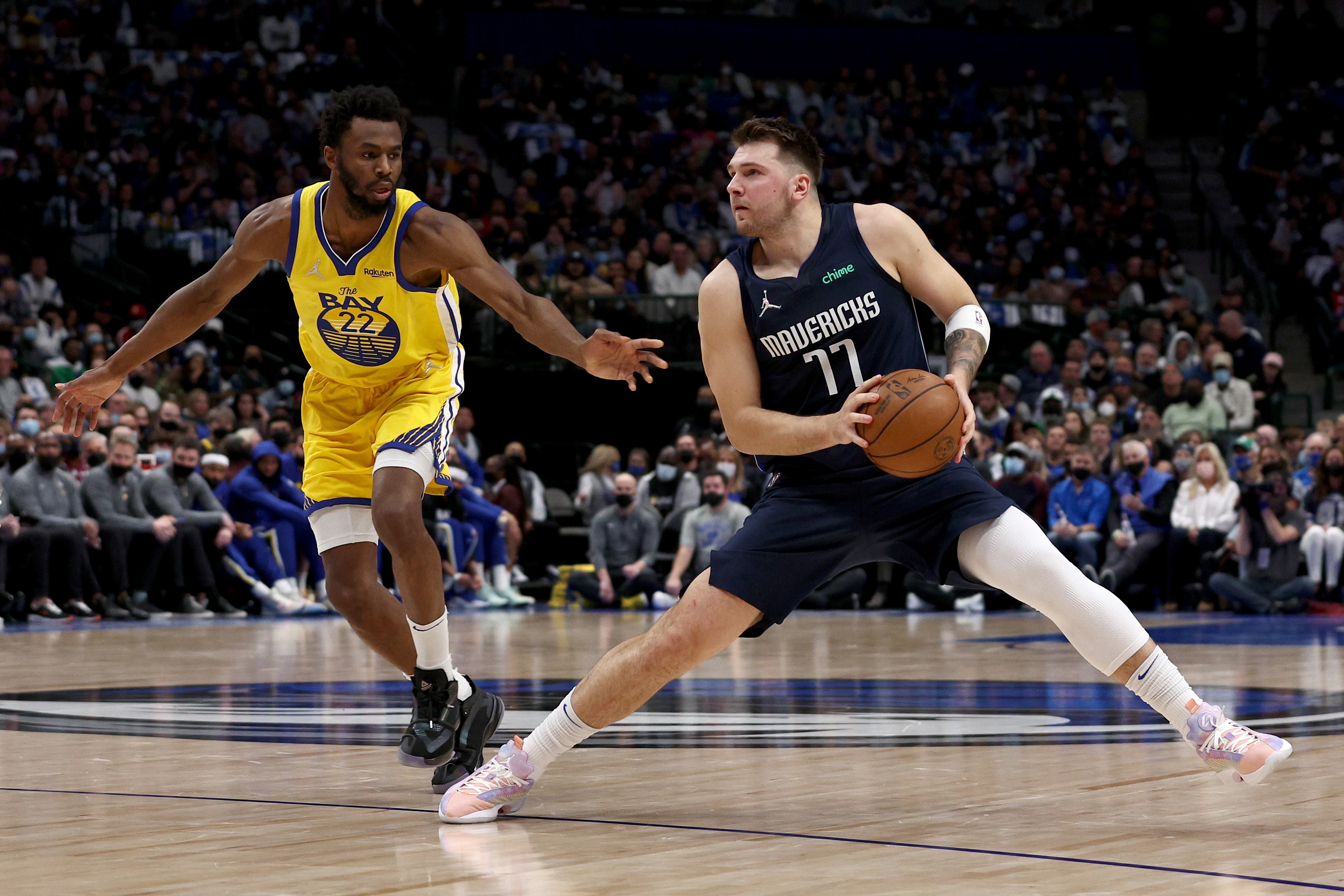 Luka Doncic (kiri) dari Dallas Mavericks menggiring bola, sementara Andrew Wiggins dari Golden State Warriors mencoba menahan.   