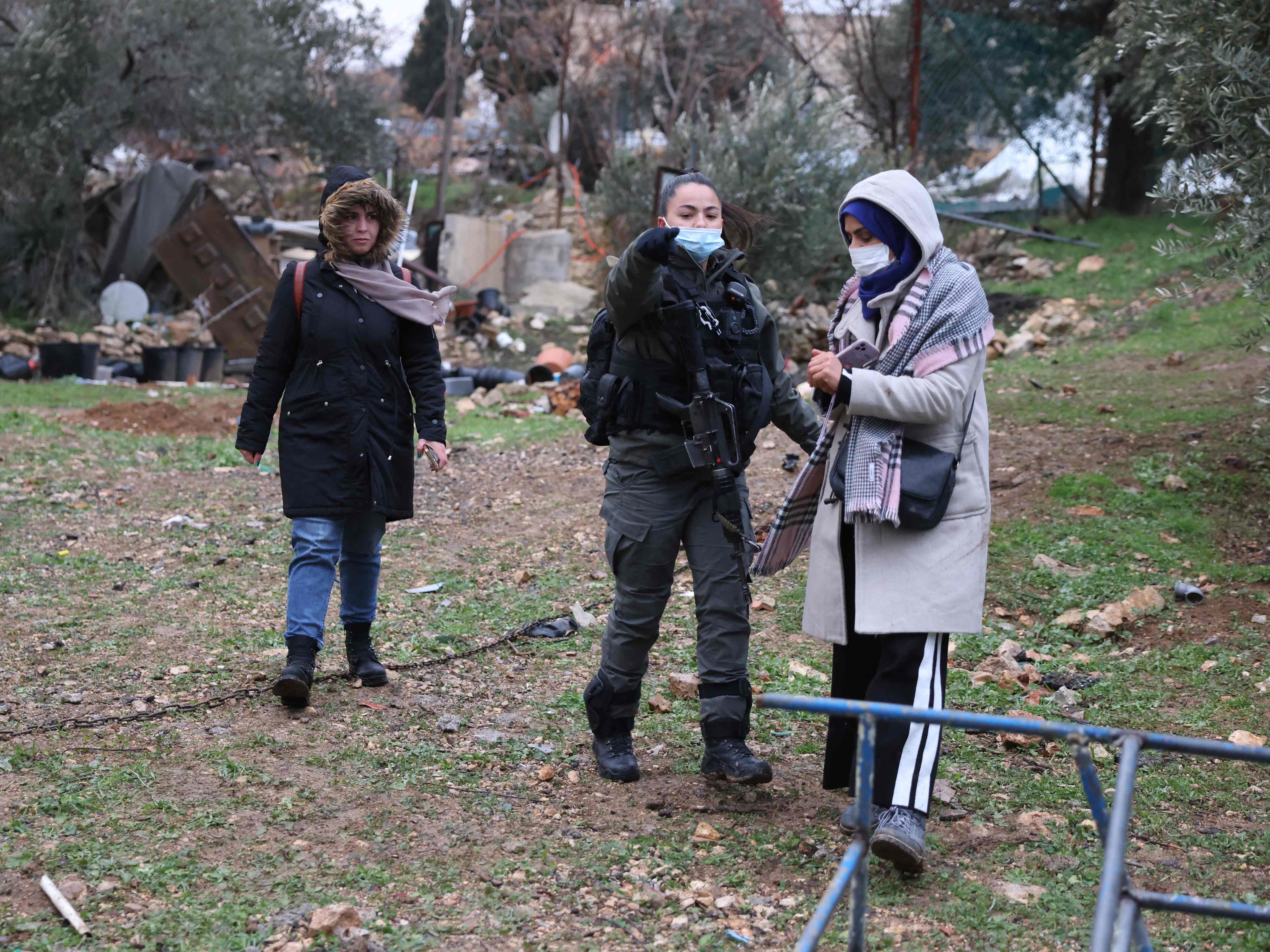 Seorang anggota pasukan Israel mengawal pendukung keluarga Salhiya Palestina menjauh dari reruntuhan rumah yang dihancurkan.