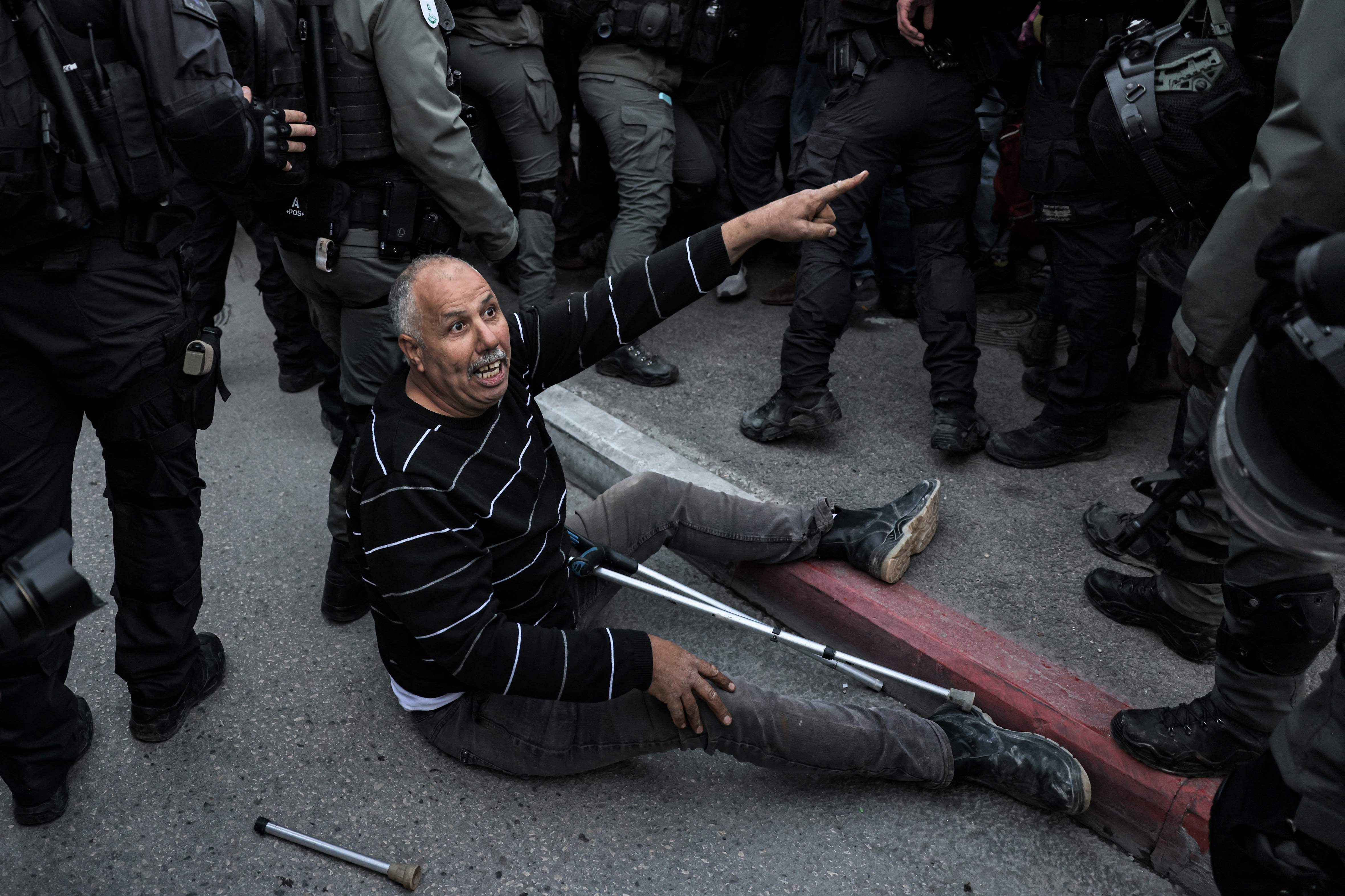 Seorang warga palestina dengan menggunakan tongkat dikelilingi tentara Israel 