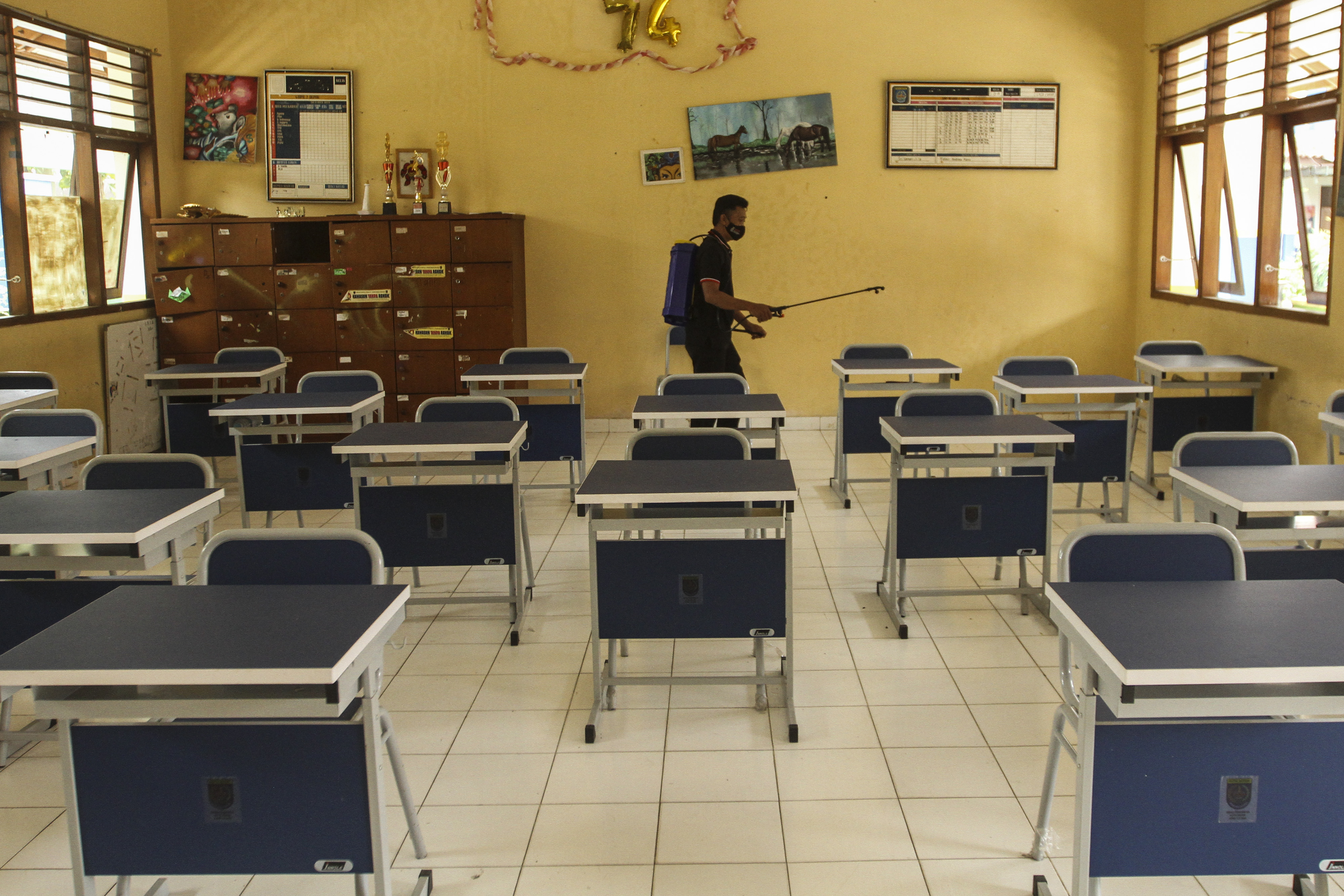 Pekerja menyemprotkan disinfektan di ruang kelas di SMPN 2 Depok, Pancoran Mas, Depok, Jawa Barat.