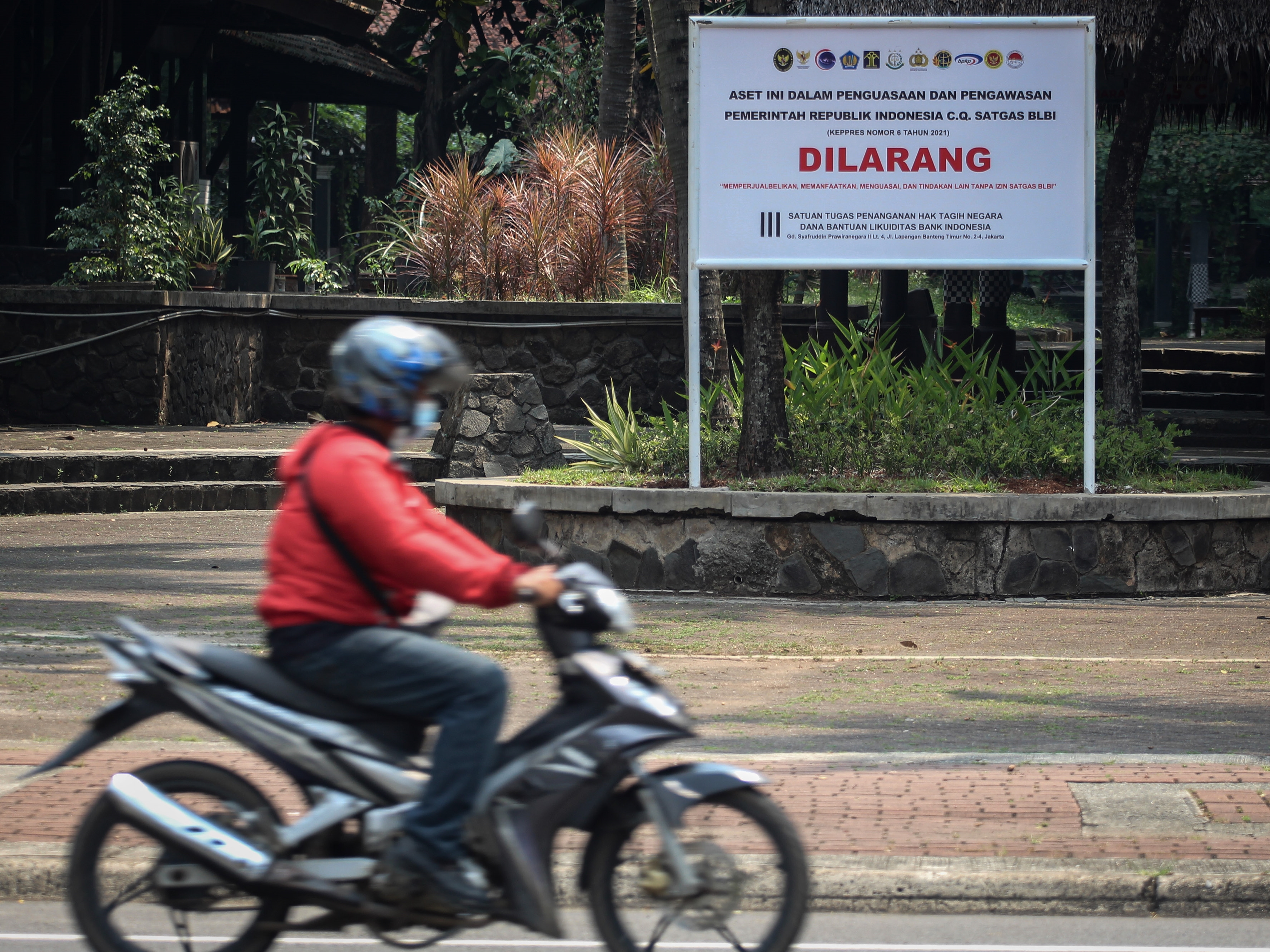 Seorang pengendara sepeda motor melintas di depan plang penyitaan aset tanah milik obligor BLBI di Kelapa Dua, Kabupaten Tangerang, Banten.