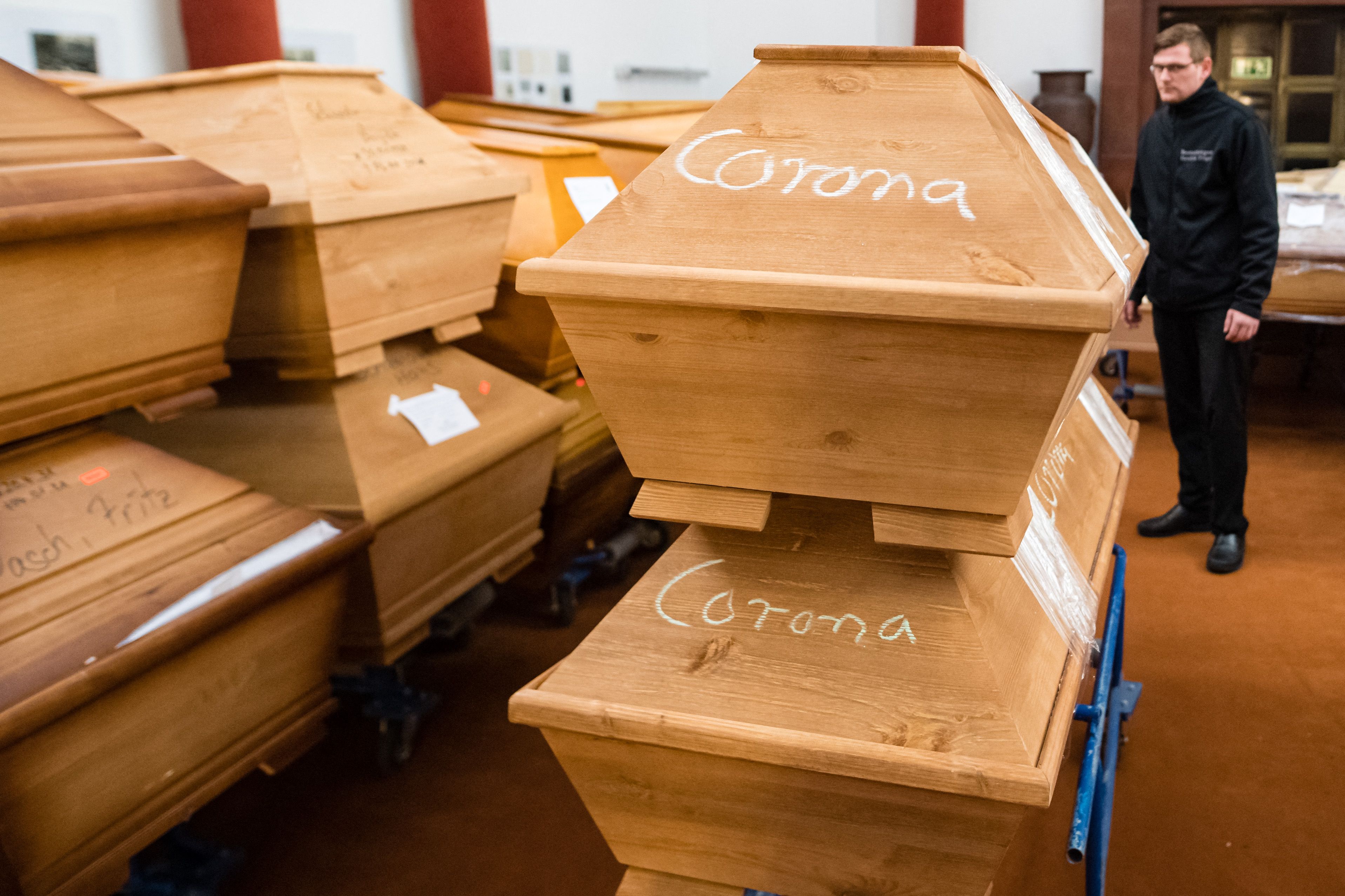 Pengurus jenazah memindahkan peti mati dengan tulisan 'Corona' di ruang duka sebelum kremasi di krematorium di Meissen, Jerman (13/1/2021) 