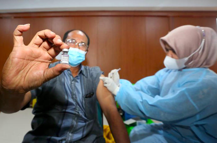 Warga menunjukkan botol vaksin buatan Pfizer saat mendapatkan suntikan vaksinasi covid-19. 