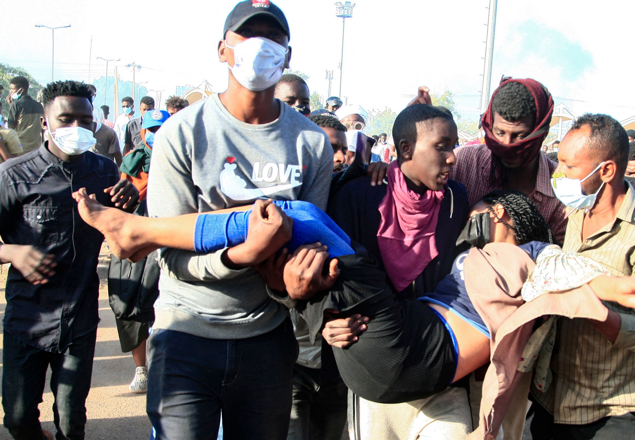 Para demonstran membawa rekannya yang terluka saat berunjuk rasa menentang kudeta di Khartoum, Sudan, Minggu (2/1). 