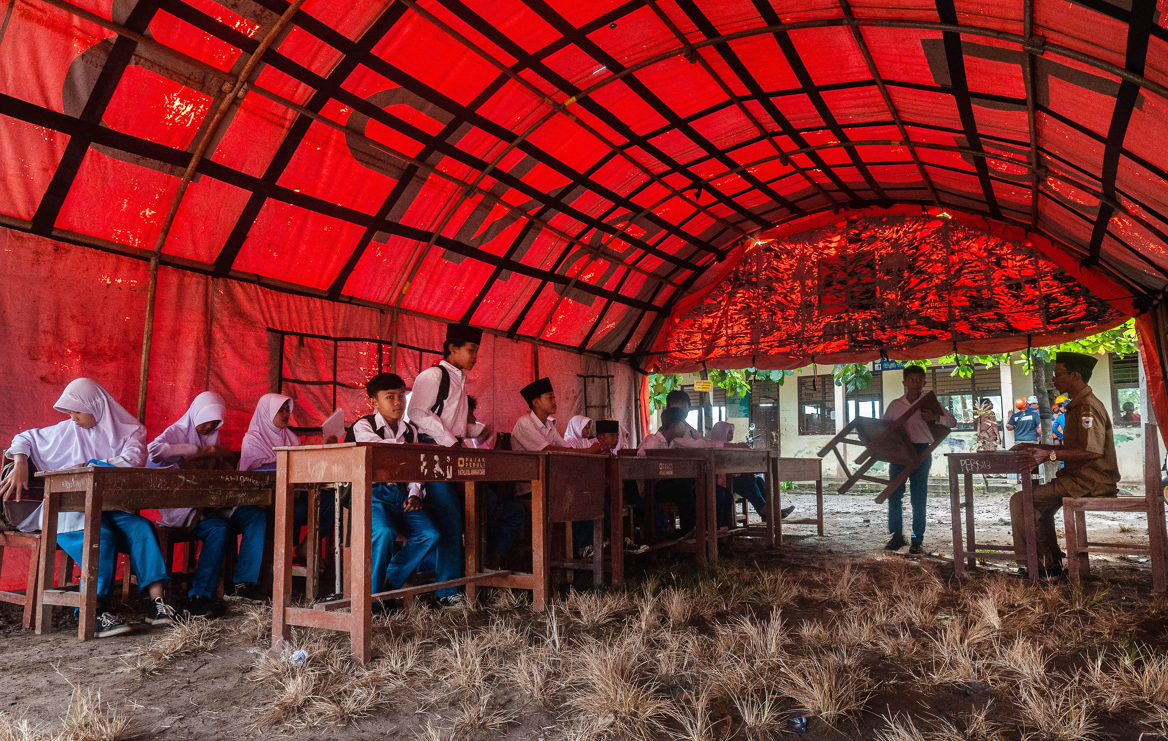 Suasana kegiatan belajar mengajar di dalam tenda sementara di MTs Mathlahul Anwar Sumur, Pandeglang, Banten.