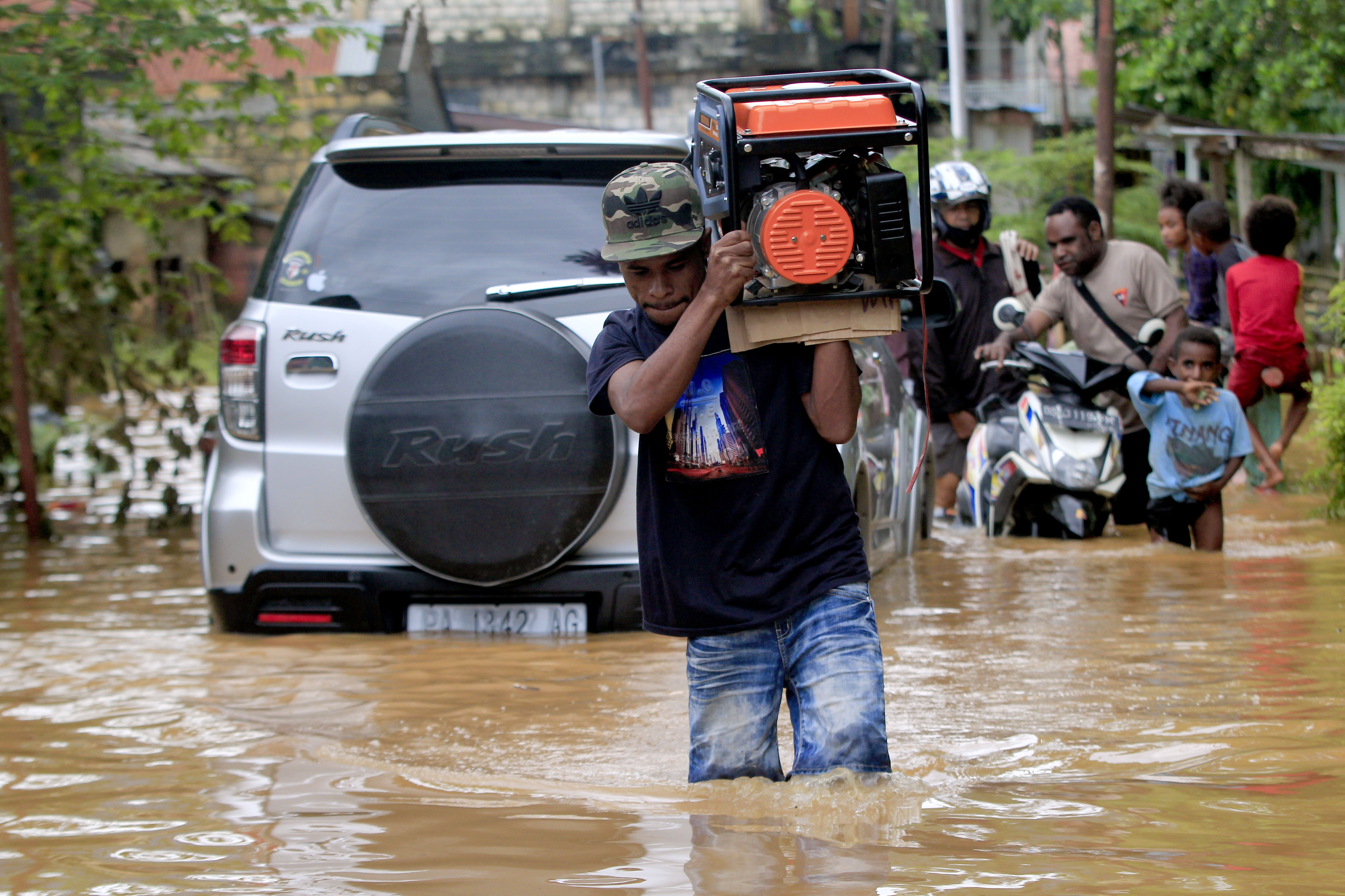Warga melintasi daerah yang masih terendam banjir di Perumahan Organda, Distri Heram, Kota Jayapura, Papua, Minggu (9/1/2022).