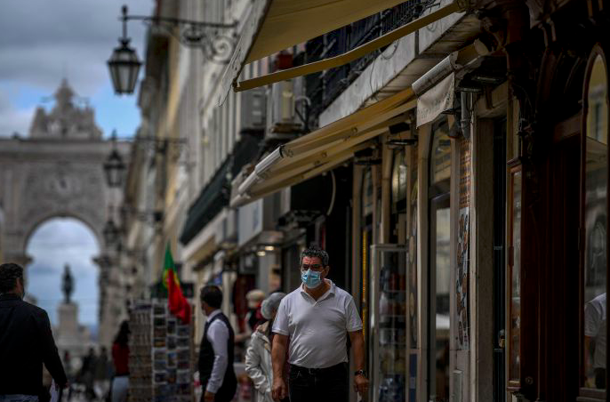 Warga mengenakan masker berjalan di pusat kota Lisabon, Portugal.