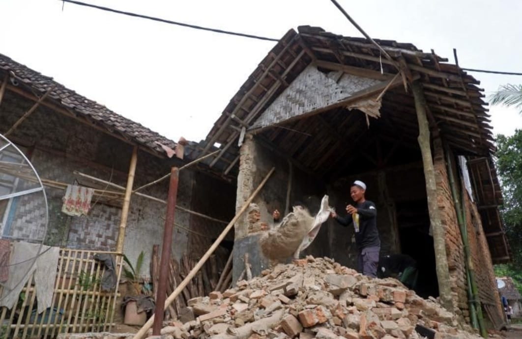 Seorang membereskan rumahnya yang hancur terkena gempa dengan magnitude 6,6 di Kabupaten Pandegkang, Banten, pada 15 Januari 2022. . 