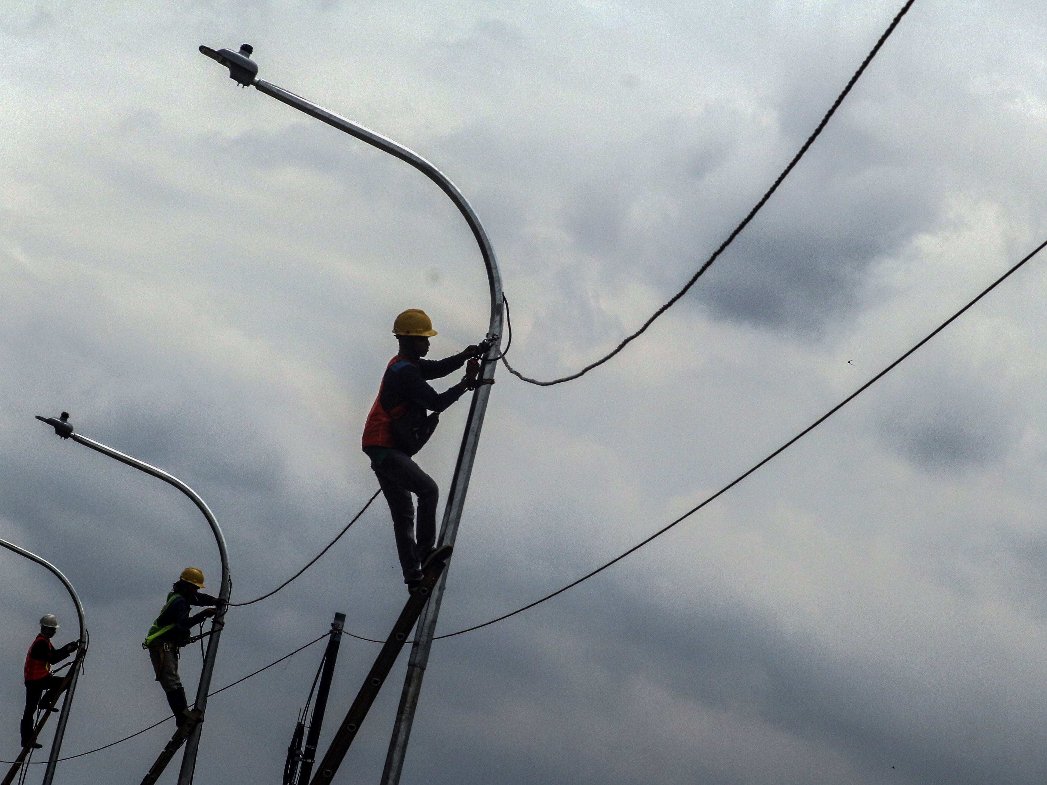 Sejumlah pekerja memasang instalasi listrik di Lingkar Dramaga, Kabupaten Bogor, Jawa Barat, Senin (22/11/2021). 