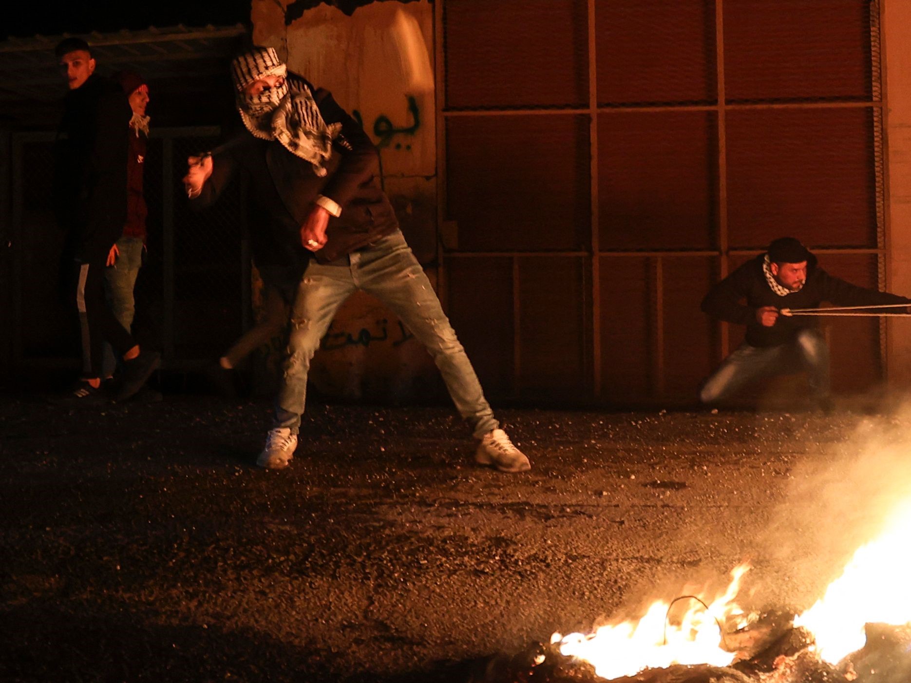 Pemuda Palestina melemparkan batu ke pasukan keamanan Israel untuk menentang kembalinya pemukim ilegal, Sabtu (1/1).