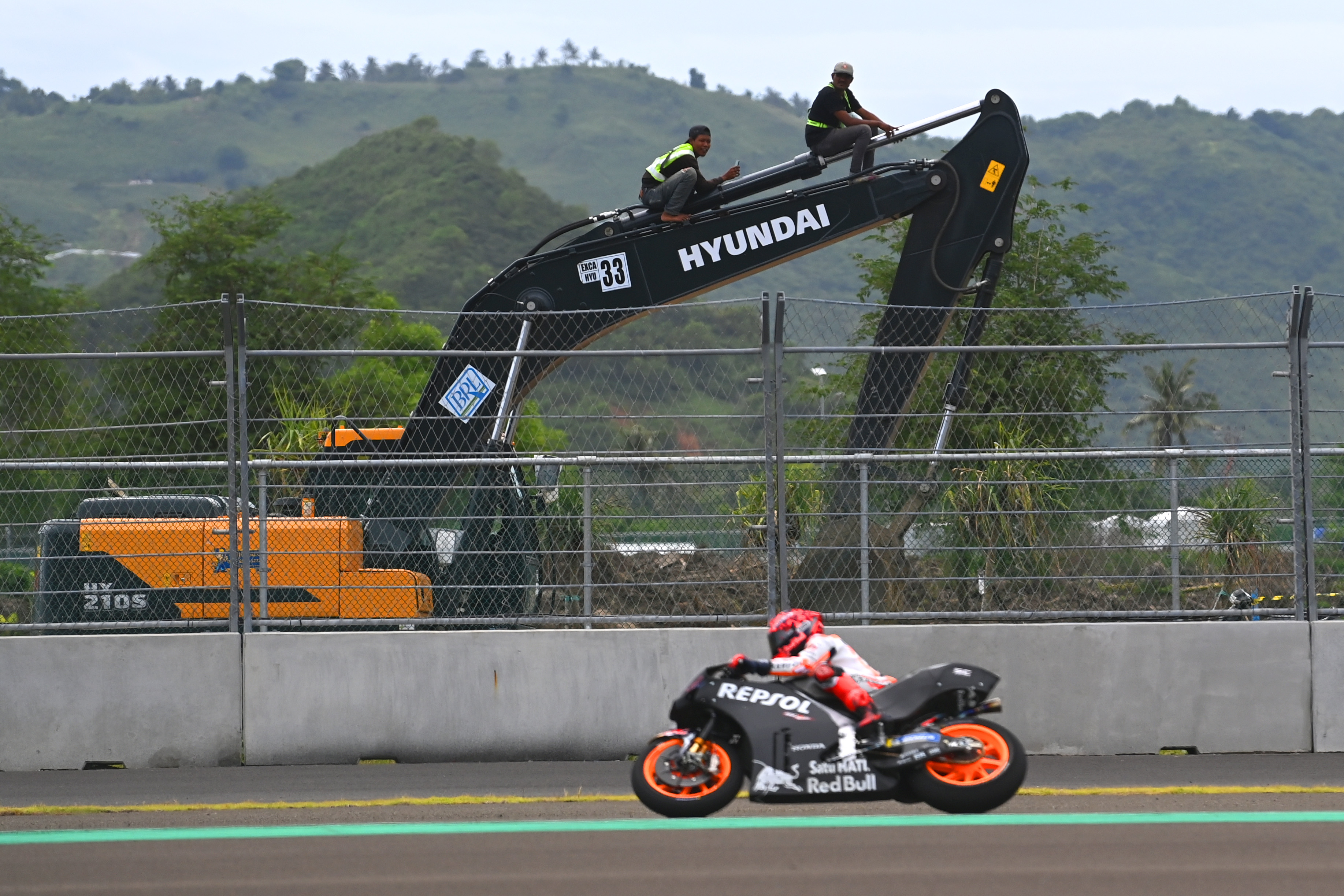 Pembalap Repsol Honda Marc MArquez melewati ekscavator masih berada di luar pagar sirkuit mandalika