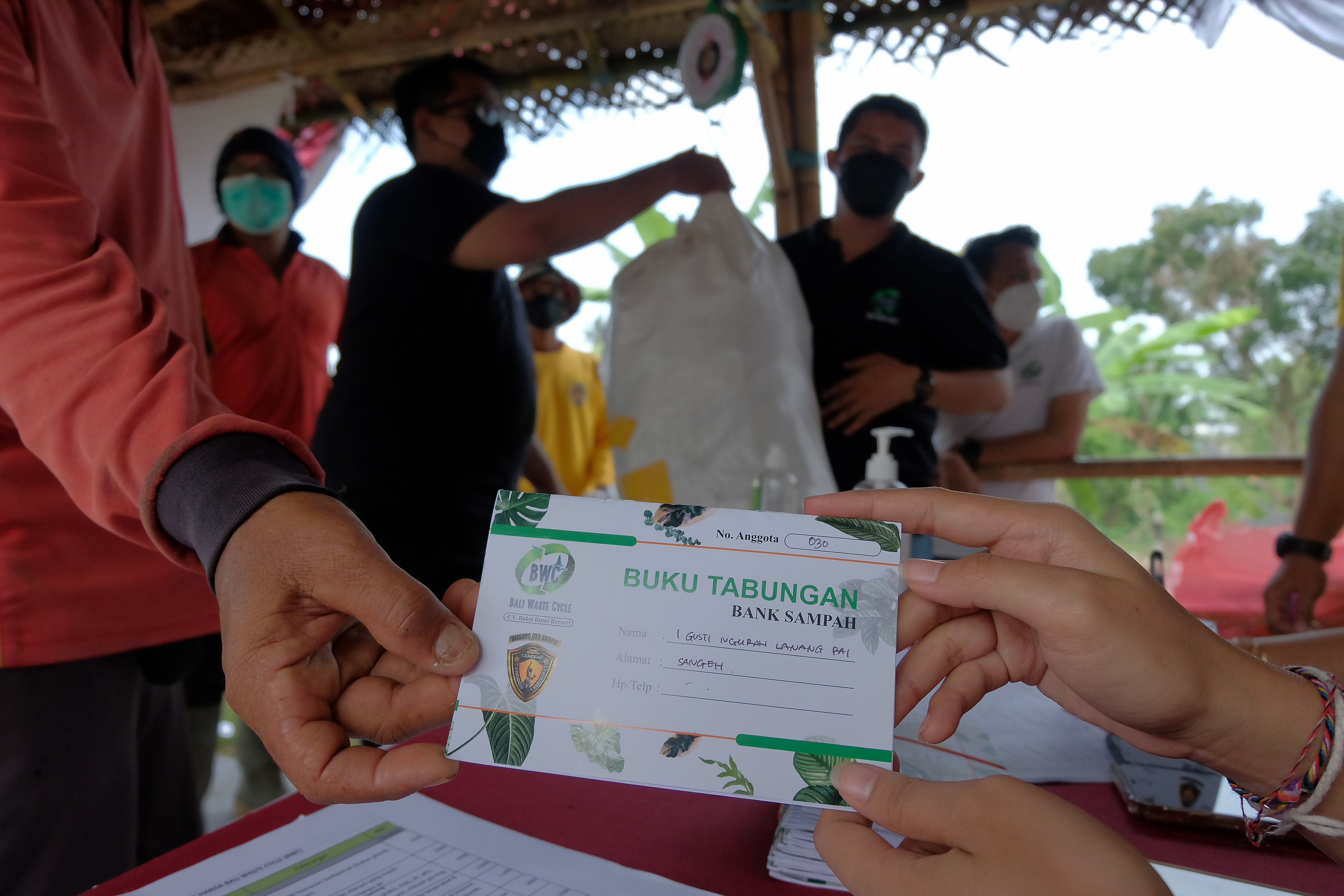  PROGRAM BANK SAMPAH: Petugas membagikan buku tabungan sampah kepada warga saat peluncuran program Warung Men Sampik di Subak Tungkub, Bali.