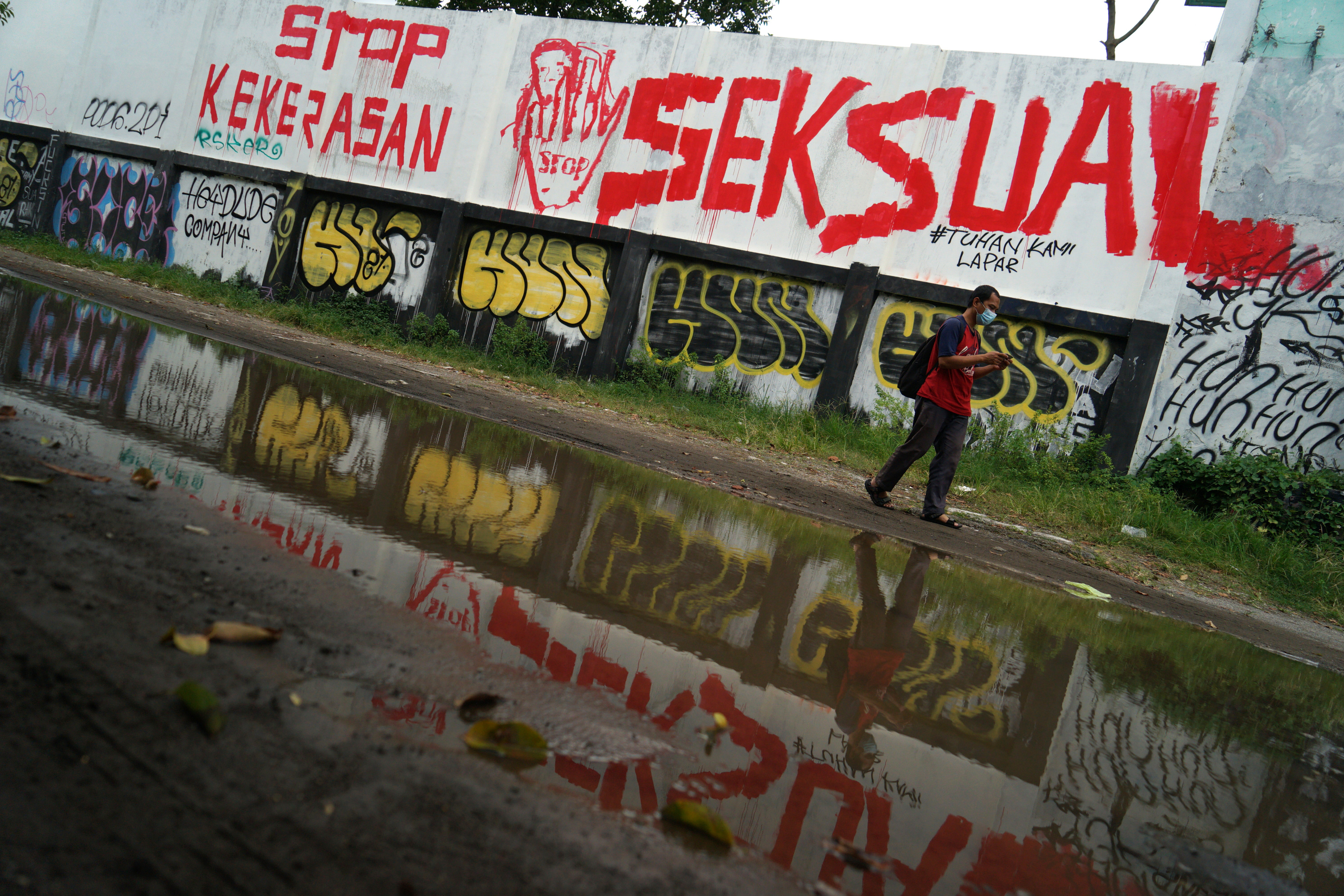 Warga melintas di dekat mural stop kekerasan seksual di Lapangan Kridosono, Yogyakarta, Senin (10/1/2022)
