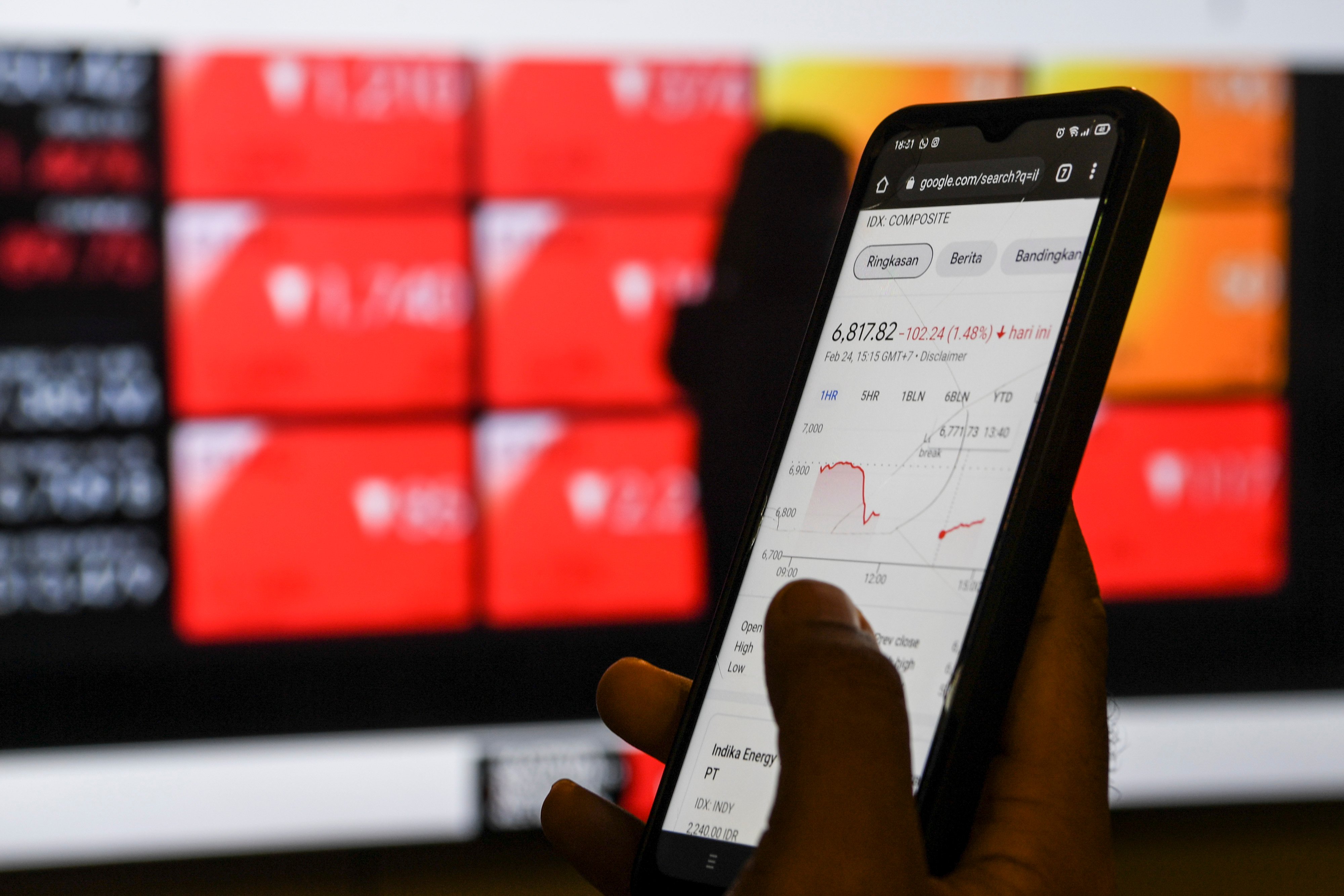 Warga melihat layar pergerakan IHSG pada gawai di tengah memanasnya konflik Rusia-Ukraina.