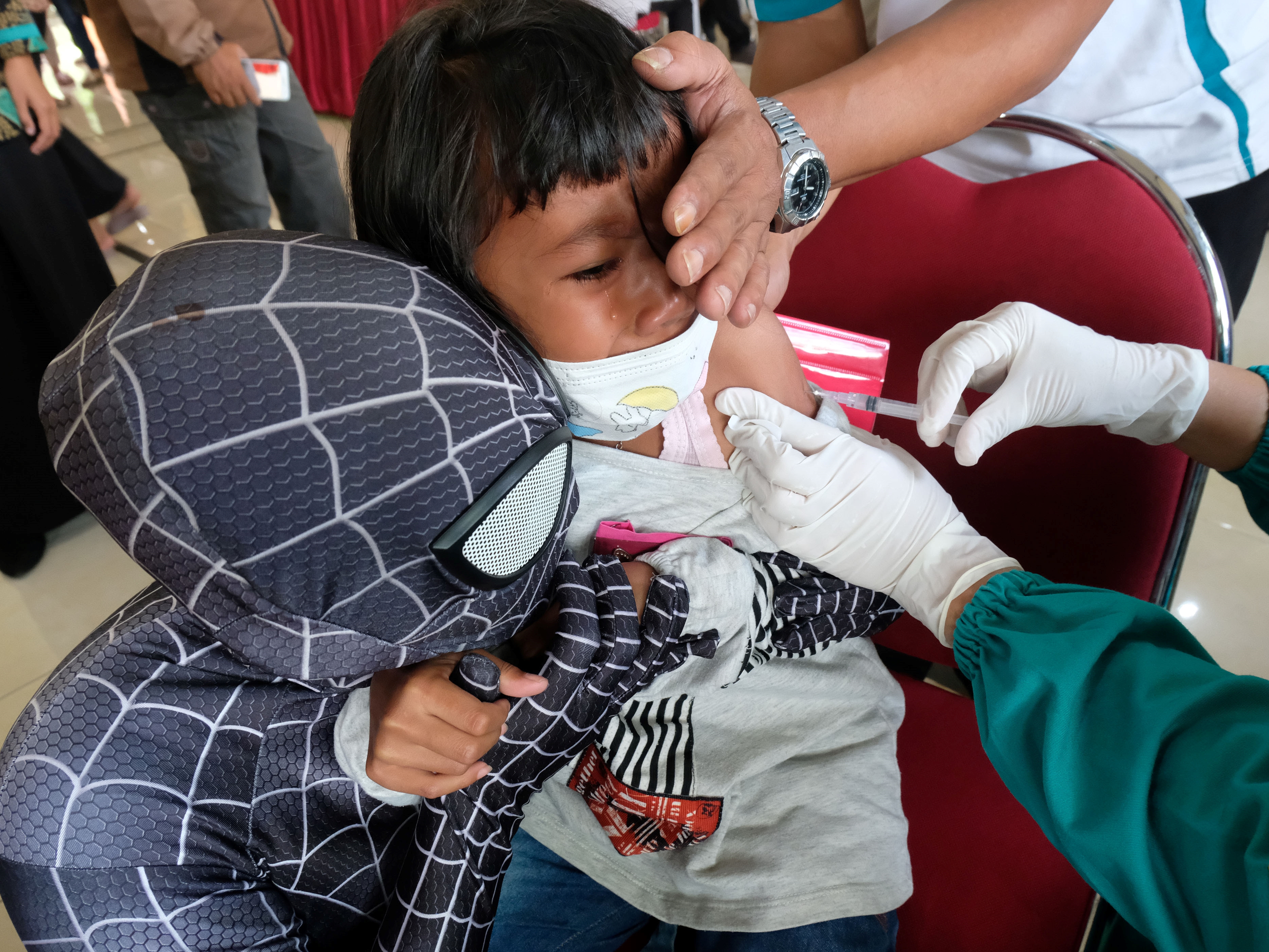 Seorang relawan berpakaian Spiderman mendampingi siswa saat vaksinasi covid-19 bagi anak umur 6-11 tahun di Muntung, Temanggung, Jateng.