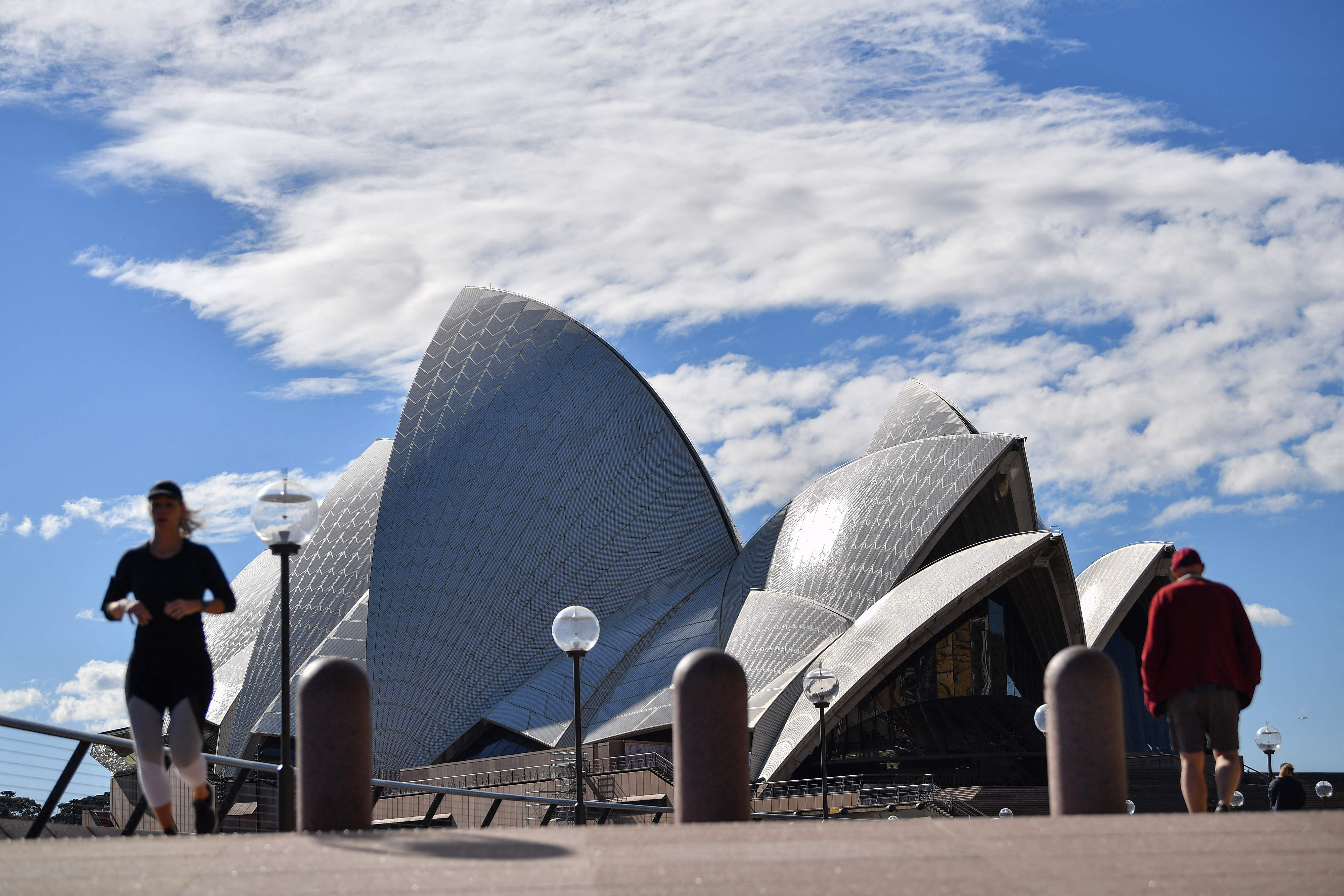 Warga berjalan di sekitar Opera House yang berlokasi di Sydney, Australia.