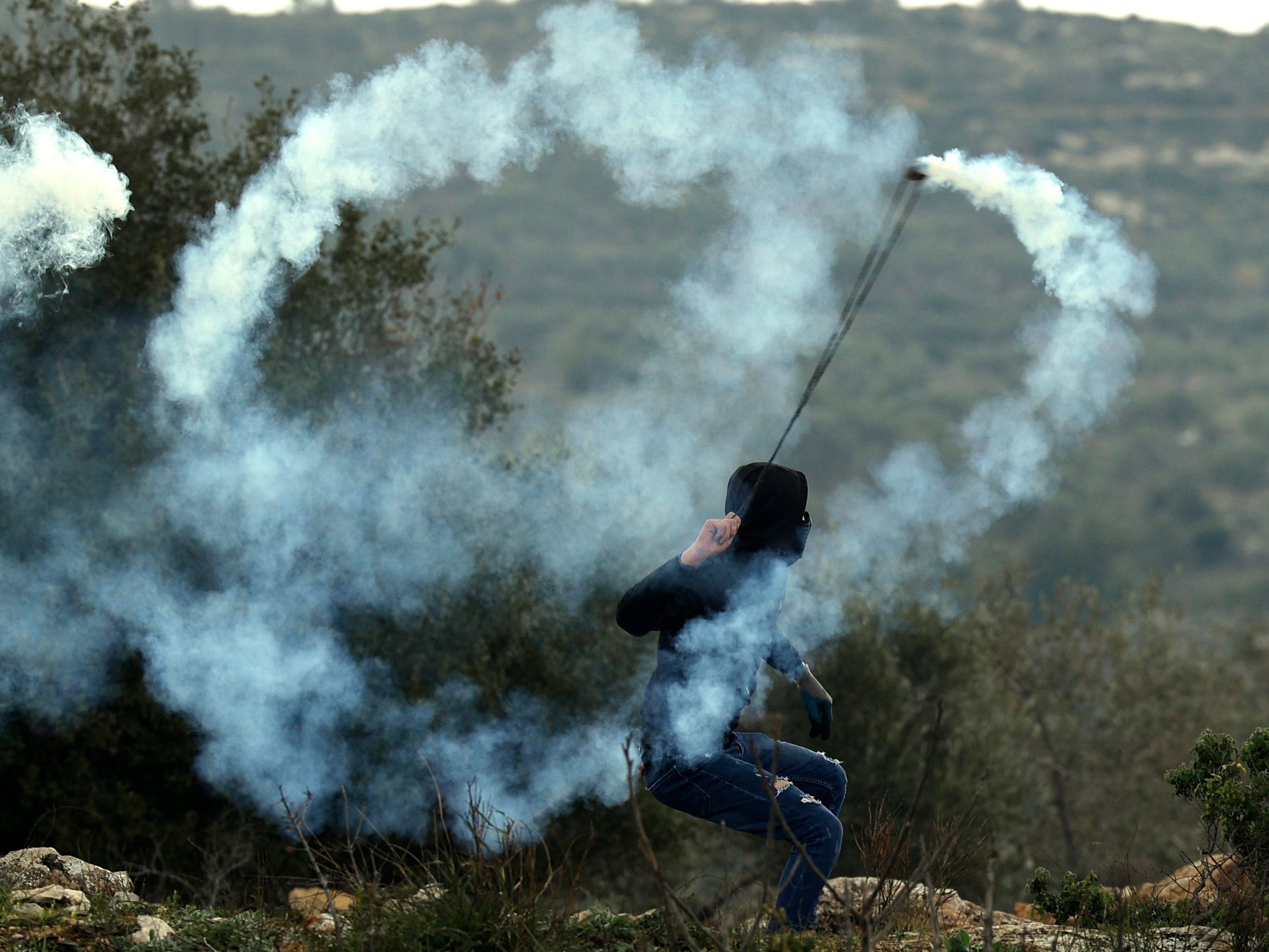 Pengunjuk rasa Palestina melemparkan tabung gas air mata ke arah pasukan keamanan Israel karena menentang pemukiman di Beita.