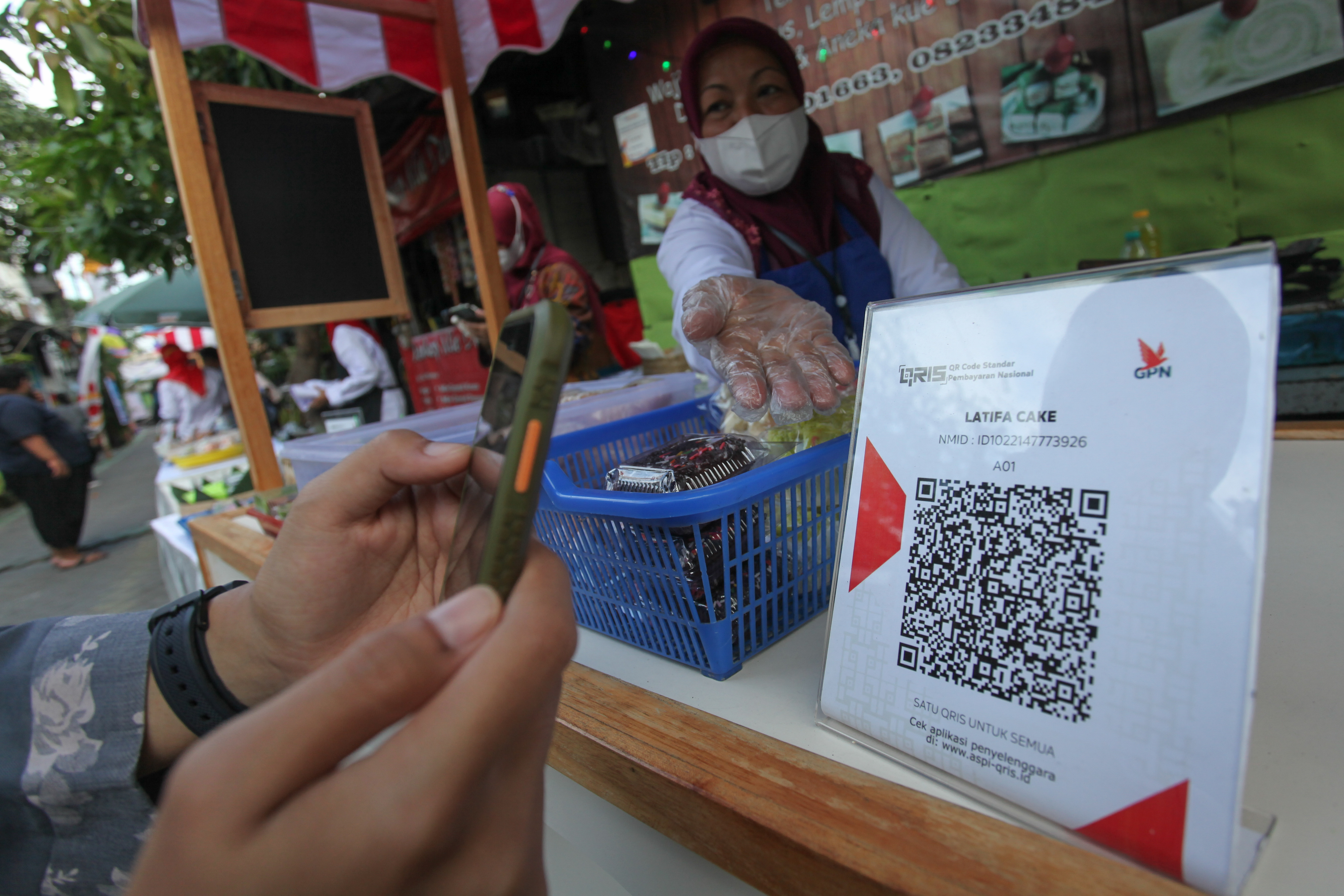 Warga melakukan pembayaran nontunai menggunakan QRIS di lapak pelaku usaha kuliner di Surabaya, Jatim,Selasa (8/2/2022). 