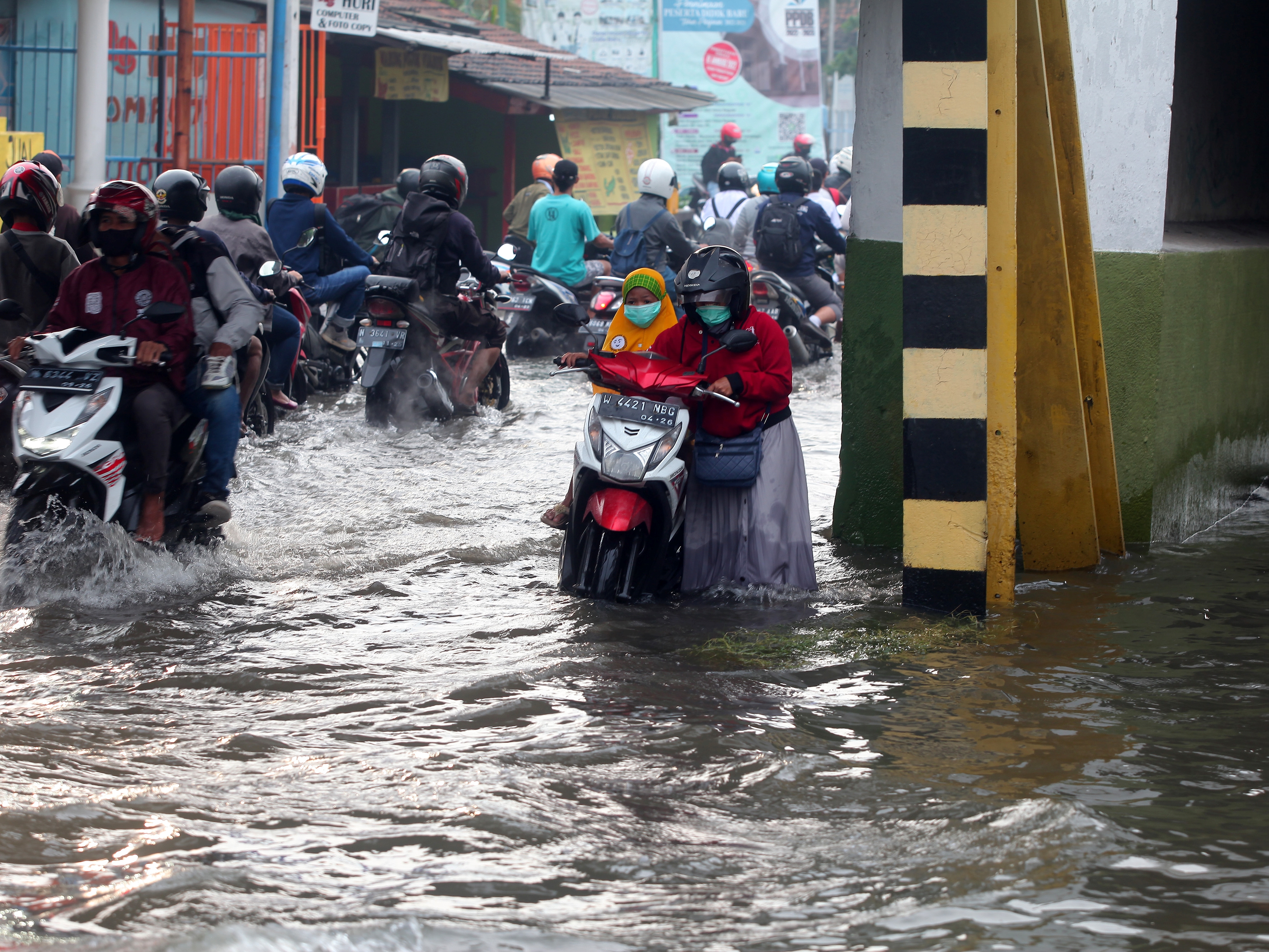  Warga mendorong sepeda motornya di Jalan Raya Gempol yang terendam banjir di Pasuruan, Jawa Timur, Senin (14/2/2022).