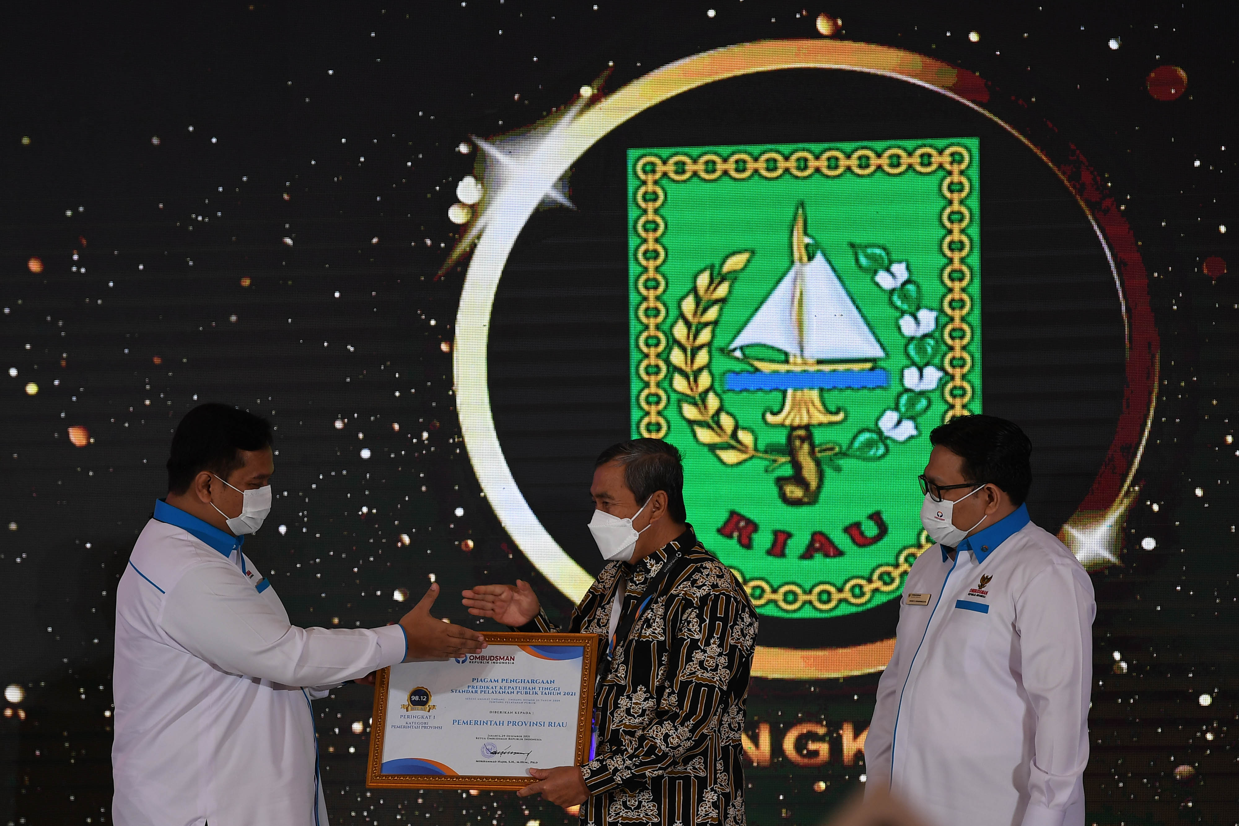 Gubernur Riau Syamsuar (batik) saat menerima penghargaan dari Ombudsman RI untuk Predikat Kepatuhan Tinggi Standar Pelayanan Publik 2021. 