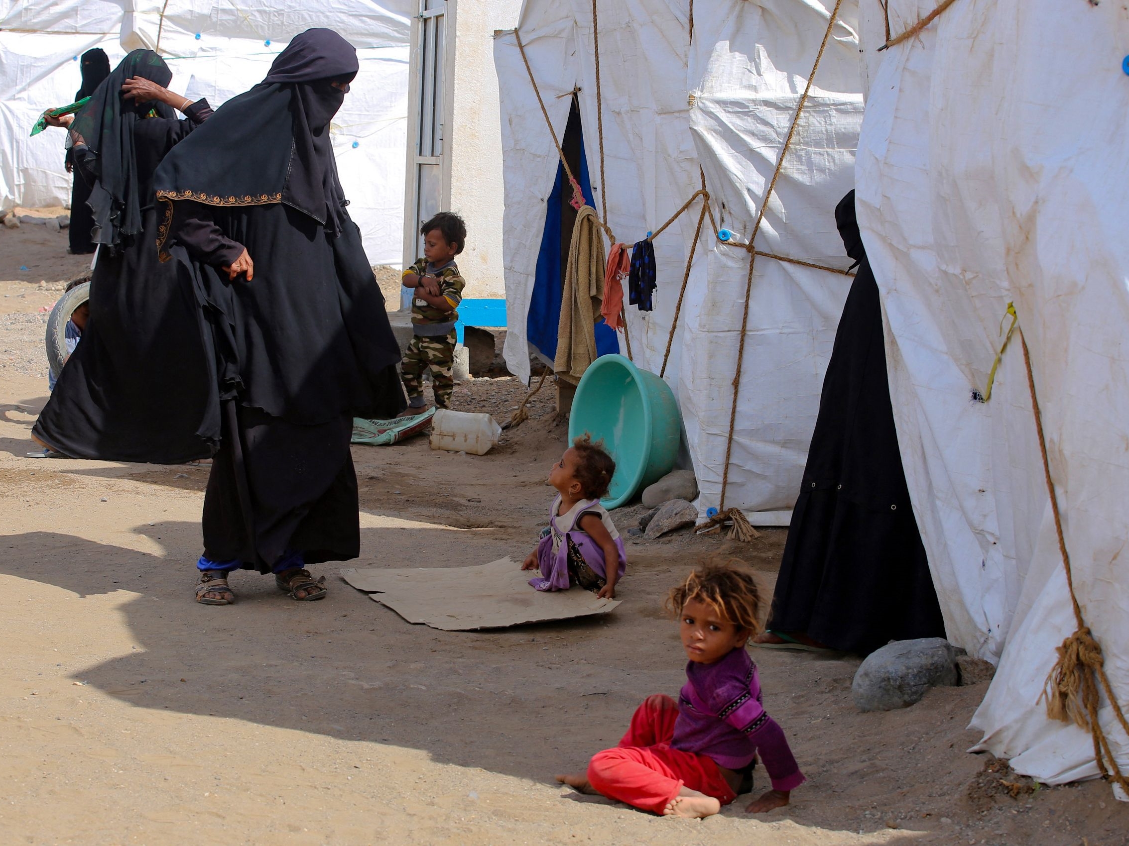 Wanita dan anak-anak berkumpul di depan tenda di kamp pengungsi Yaman yang melarikan diri dari pertempuran.