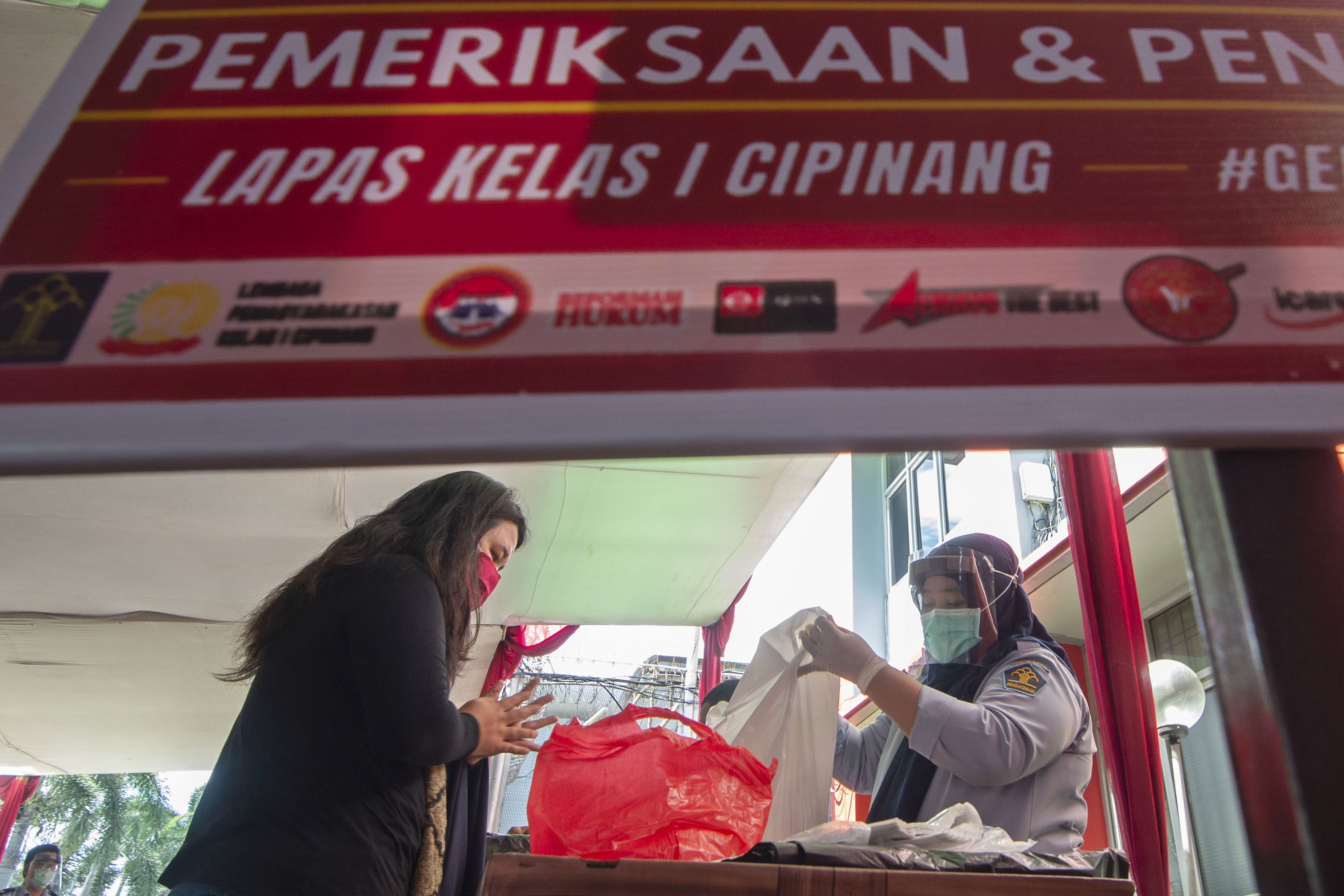 Petugas memeriksa barang bawaan keluarga yang akan diberikan kepada warga binaan Lembaga Pemasyarakatan Kelas I Cipinang di Jakarta.