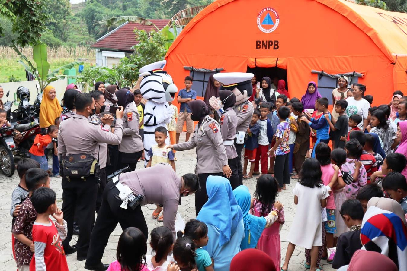 Polwan Polres Tegaal sedang menuntut anak pengungsi bermain.